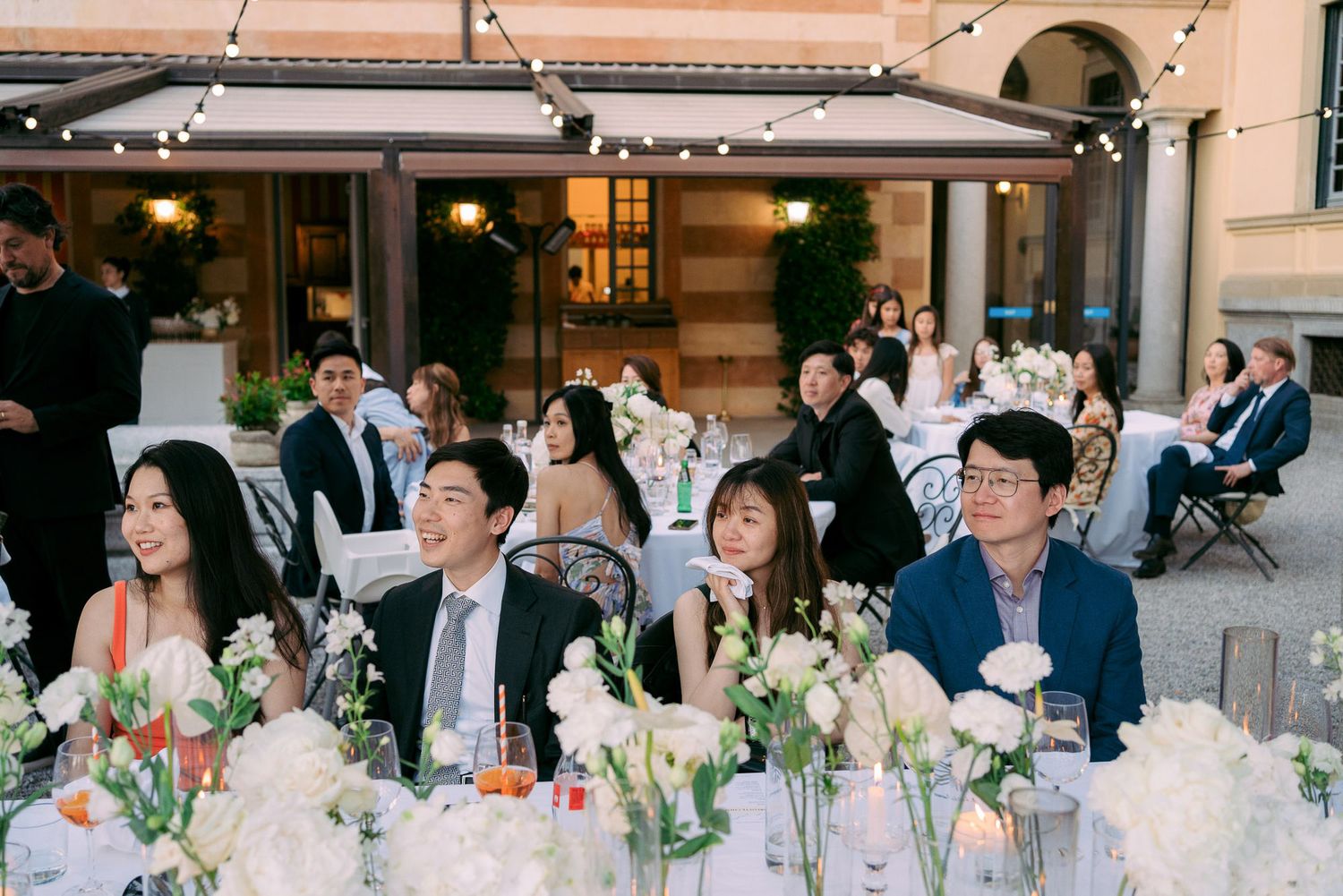 Elegant wedding reception tables decorated with floral centerpieces and candles in a sophisticated indoor venue.