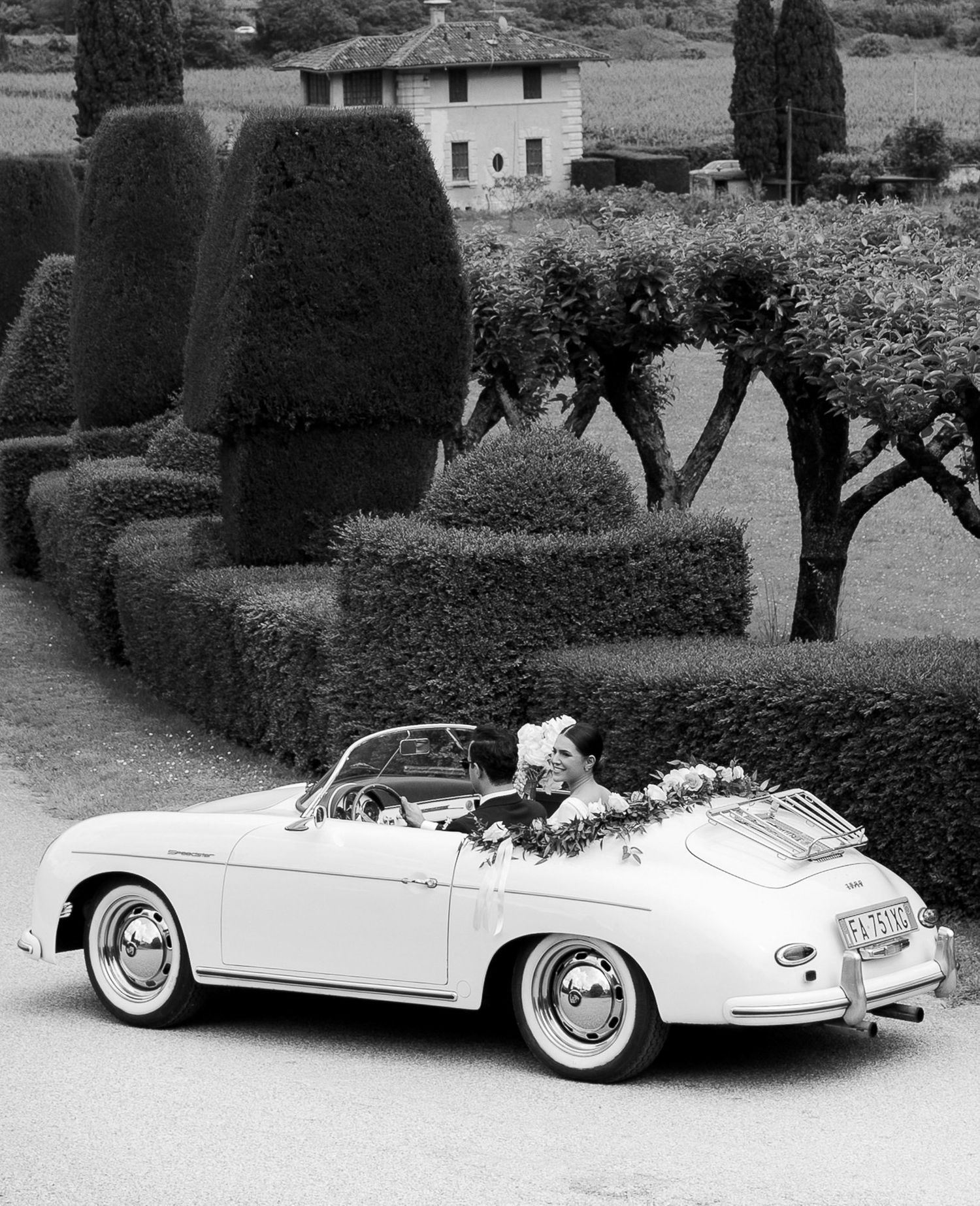 Classic white vintage convertible car decorated with flowers and ribbons for a wedding celebration.