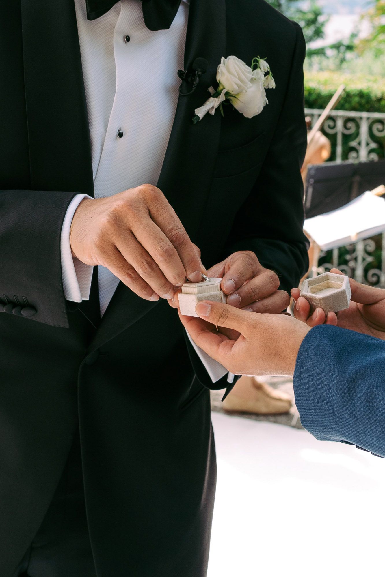 Close-up sequence of hands exchanging wedding rings during a formal ceremony with black tuxedo visible.