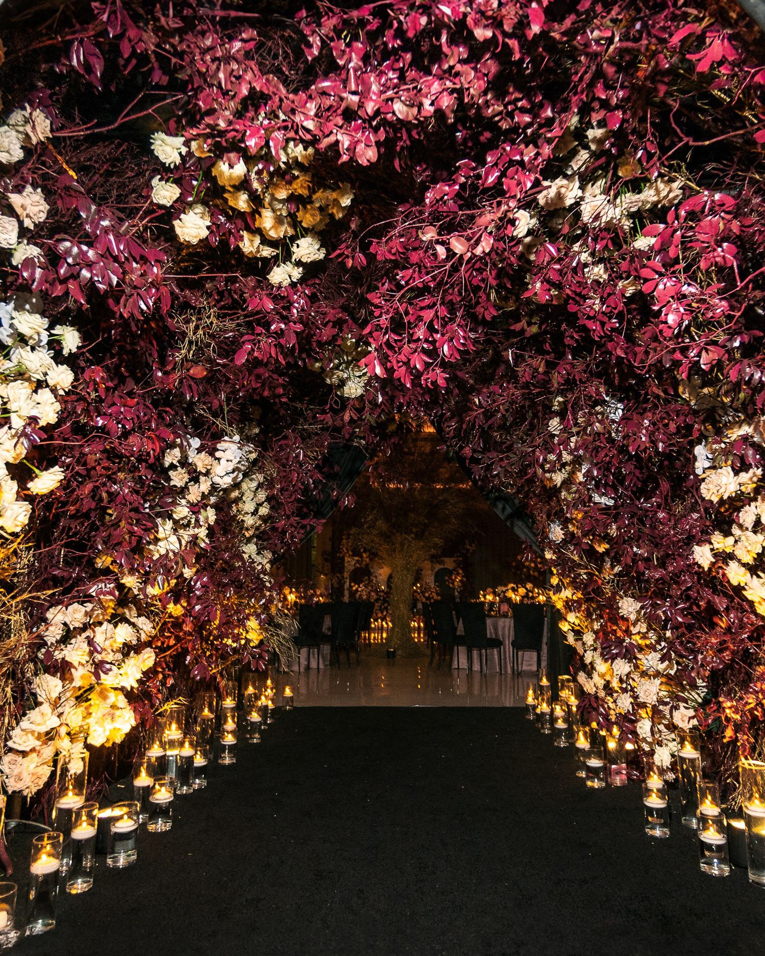 Pink cherry blossoms illuminated at night create a romantic canopy over an outdoor wedding reception setting.
