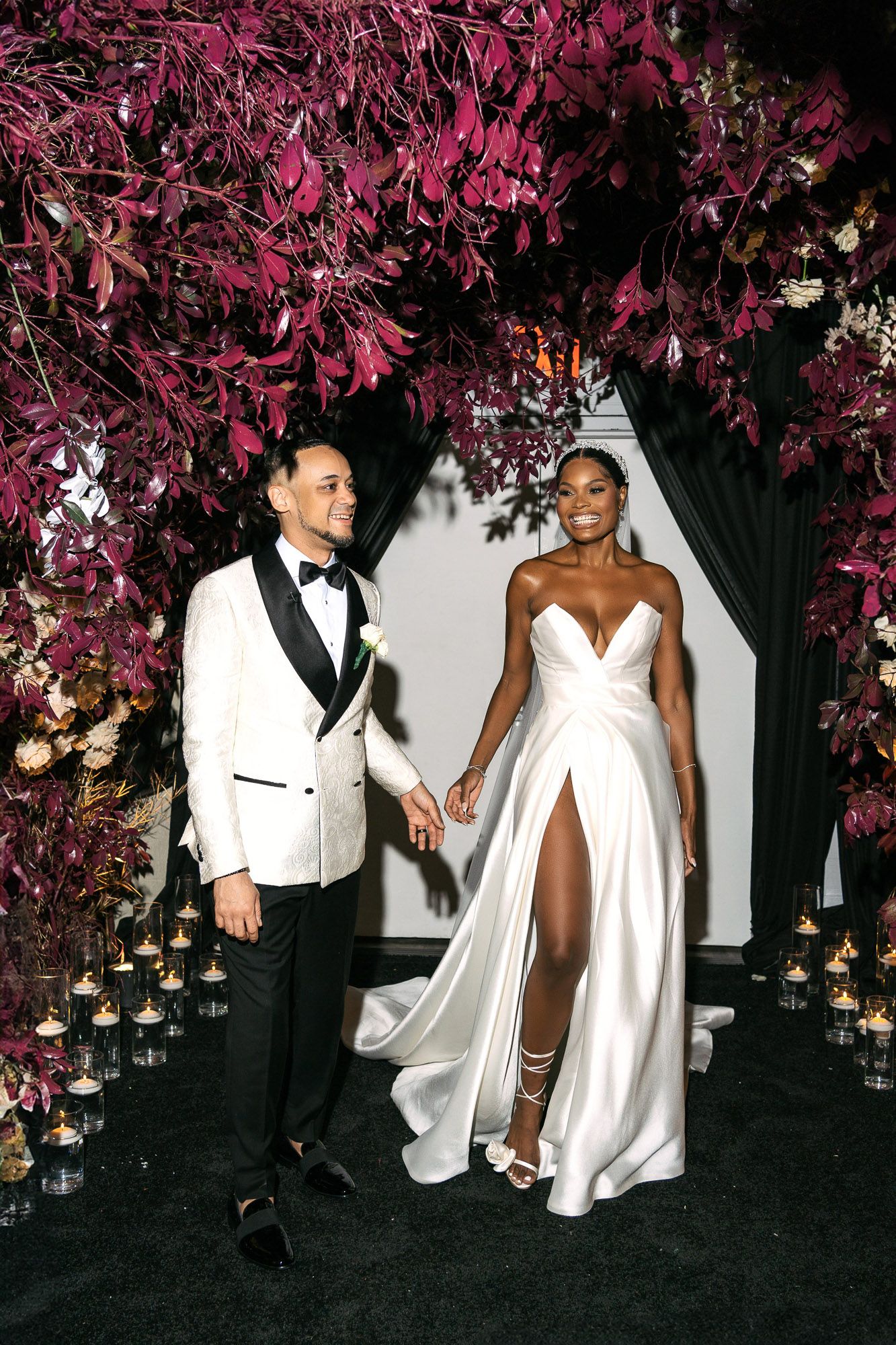 Wedding celebration under illuminated pink cherry blossoms with elegant white attire and romantic ambiance.