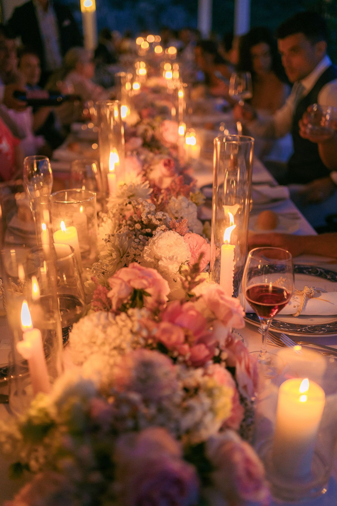 Elegant candlelit wedding reception table decorated with pink and white floral centerpieces creating a romantic atmosphere.