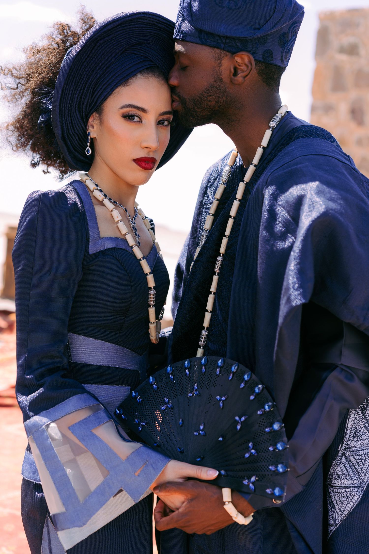 Stylish fashion photoshoot featuring a couple in dark blue and black outfits with elegant accessories.