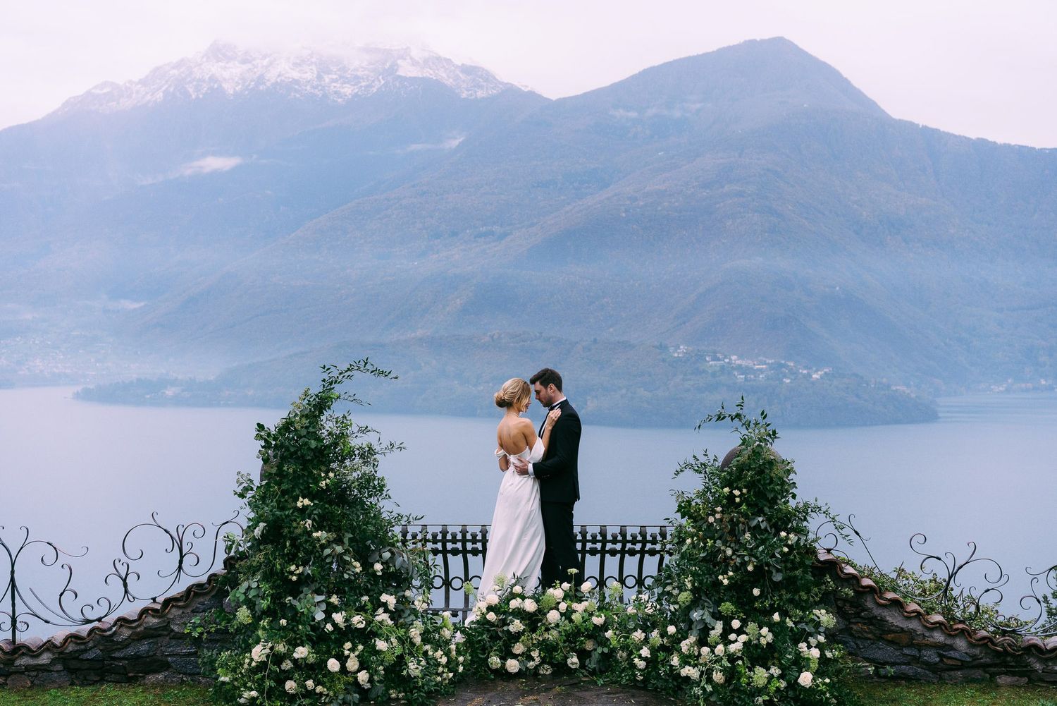 Scenic mountain landscape overlooking a tranquil lake with misty peaks in the background.