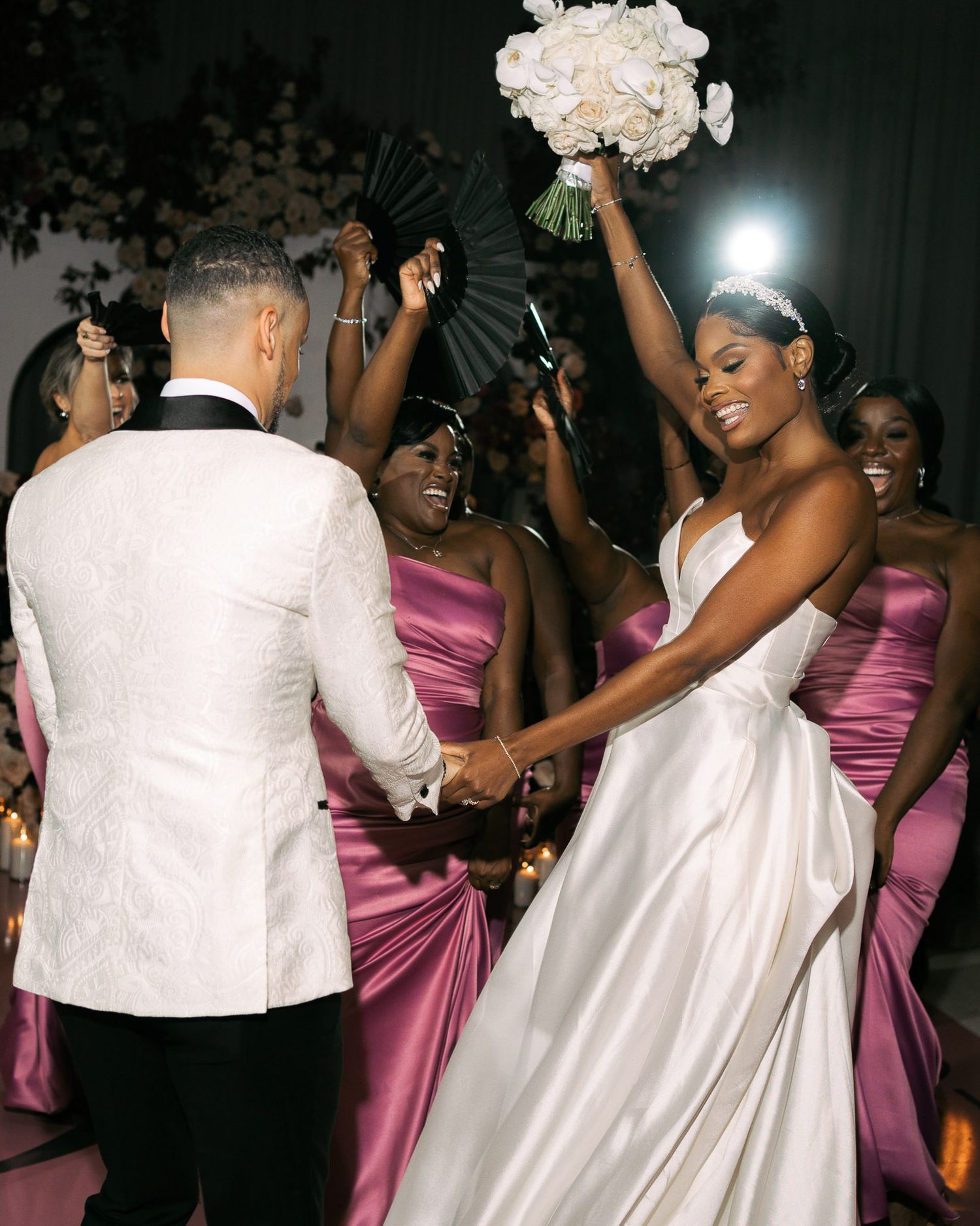 Wedding party dancing and celebrating on the dance floor at an elegant reception with bridesmaids in pink dresses.