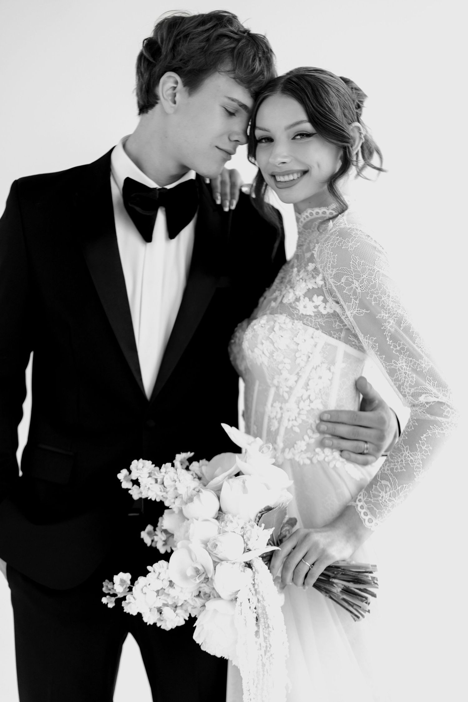Romantic black and white wedding photo series showing intimate moments between a couple in formal attire with white flowers.