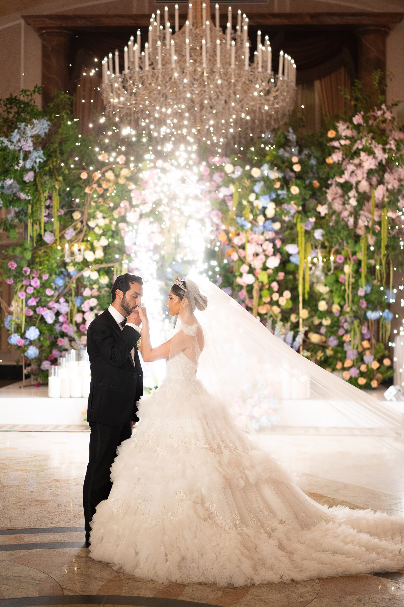 Romantic indoor wedding ceremony decorated with floral arrangements and hanging lights creating a magical atmosphere.