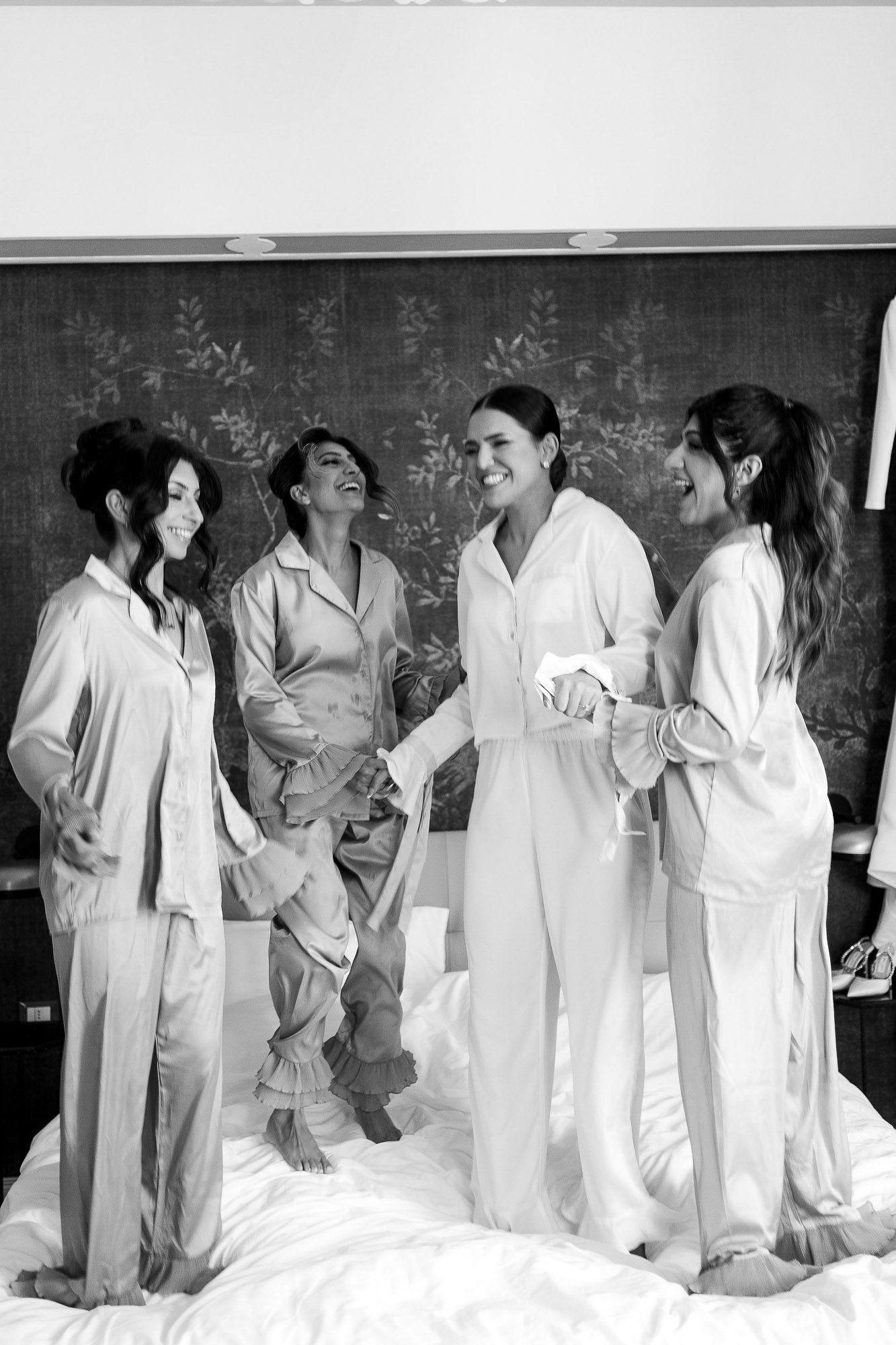 A group in matching white pajamas share laughter while standing against a chalkboard in a casual setting.
