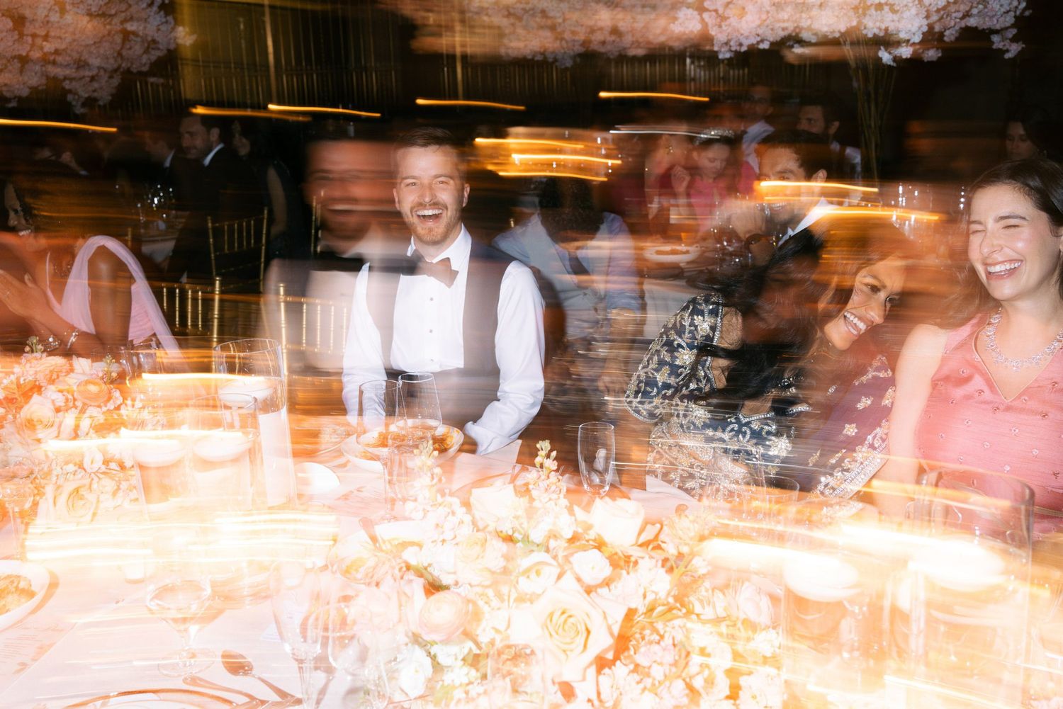 Blurred motion shot of diners and staff in a busy restaurant with warm lighting and exposed brick walls.
