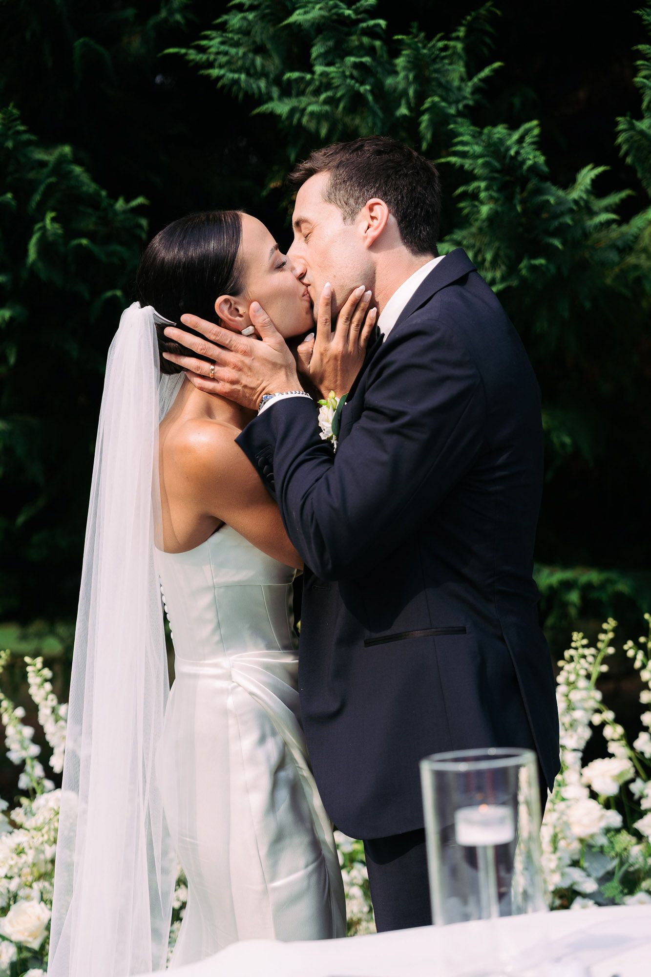 A romantic wedding sequence shows a couple sharing their first kiss as newlyweds at an outdoor garden ceremony.