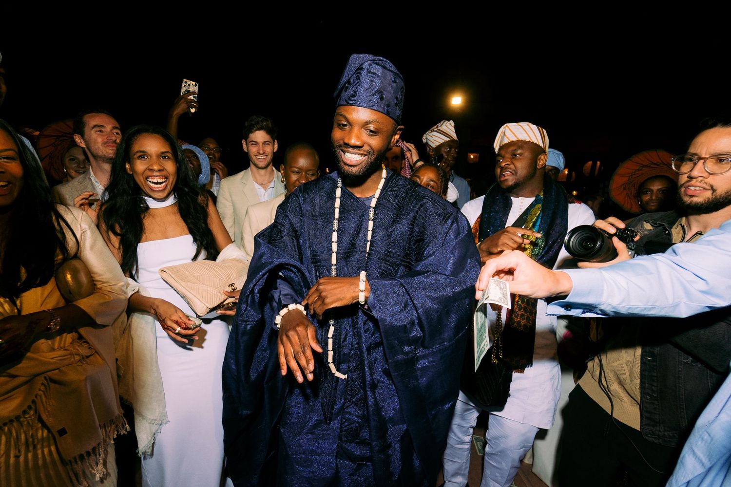 A festive celebration with attendees dressed in traditional navy blue attire and white garments during a nighttime event.