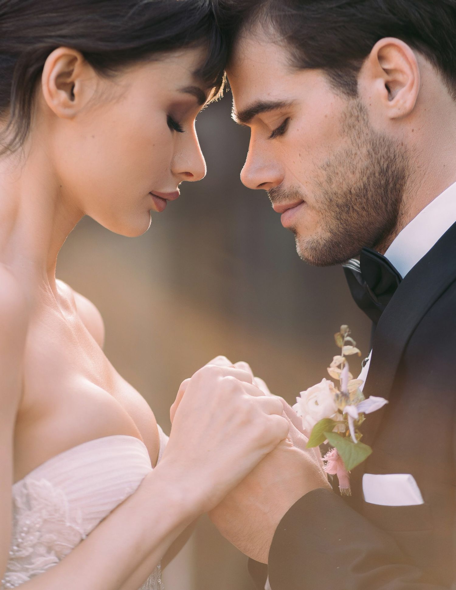 Romantic couple in wedding attire share intimate moments in soft lighting during elegant photo session.