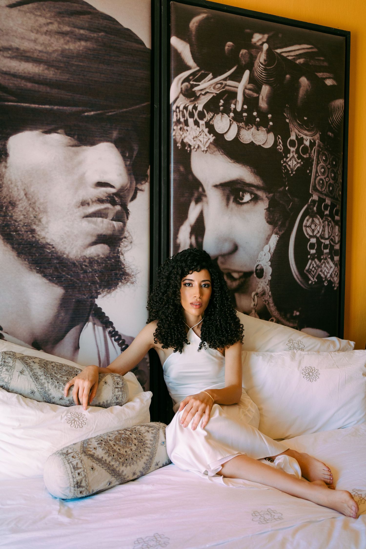 A glamorous photoshoot setup with black and white portraits displayed above white bedding.
