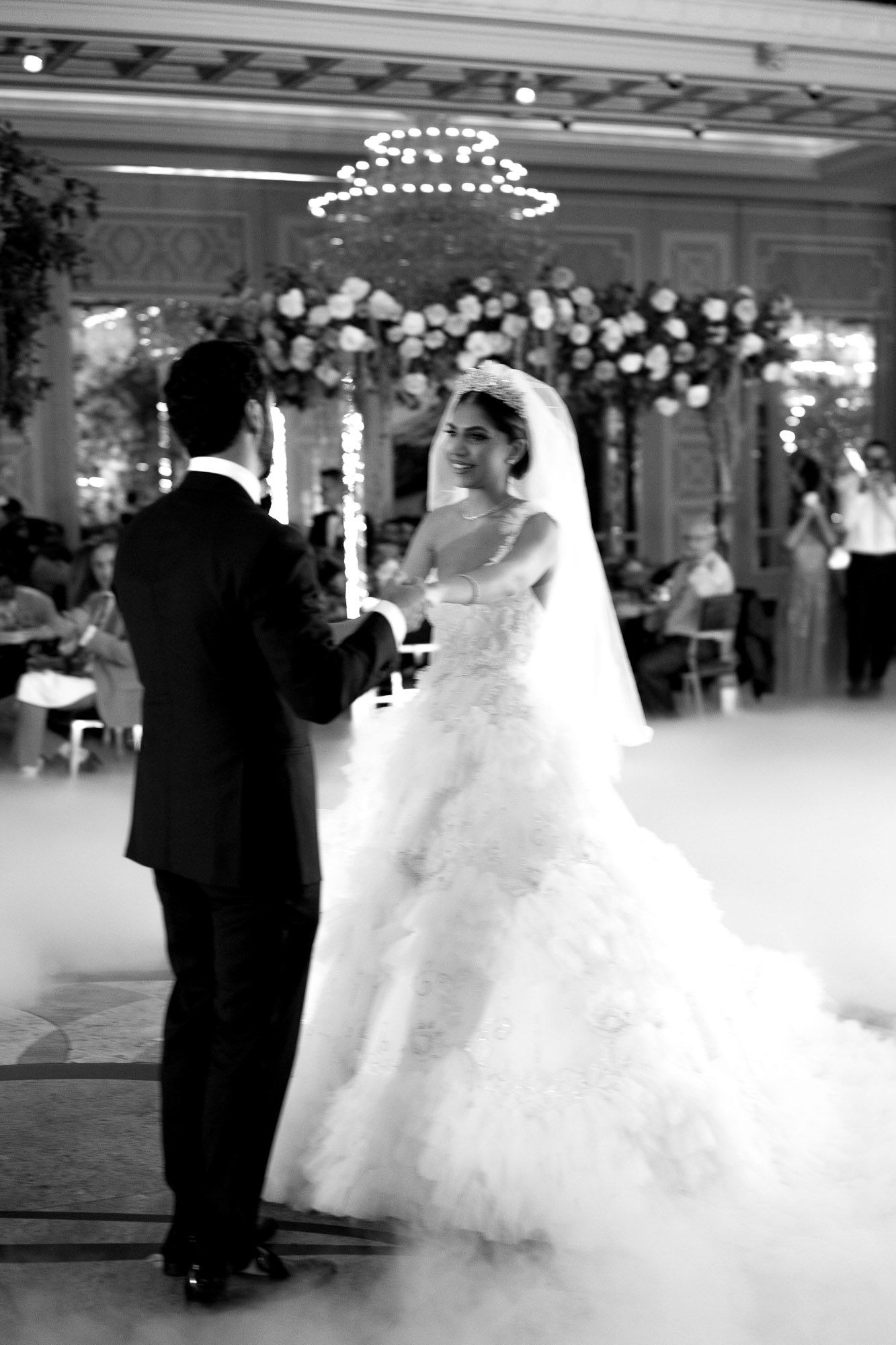 A romantic first dance between newlyweds surrounded by fog effects on an elegant ballroom dance floor.