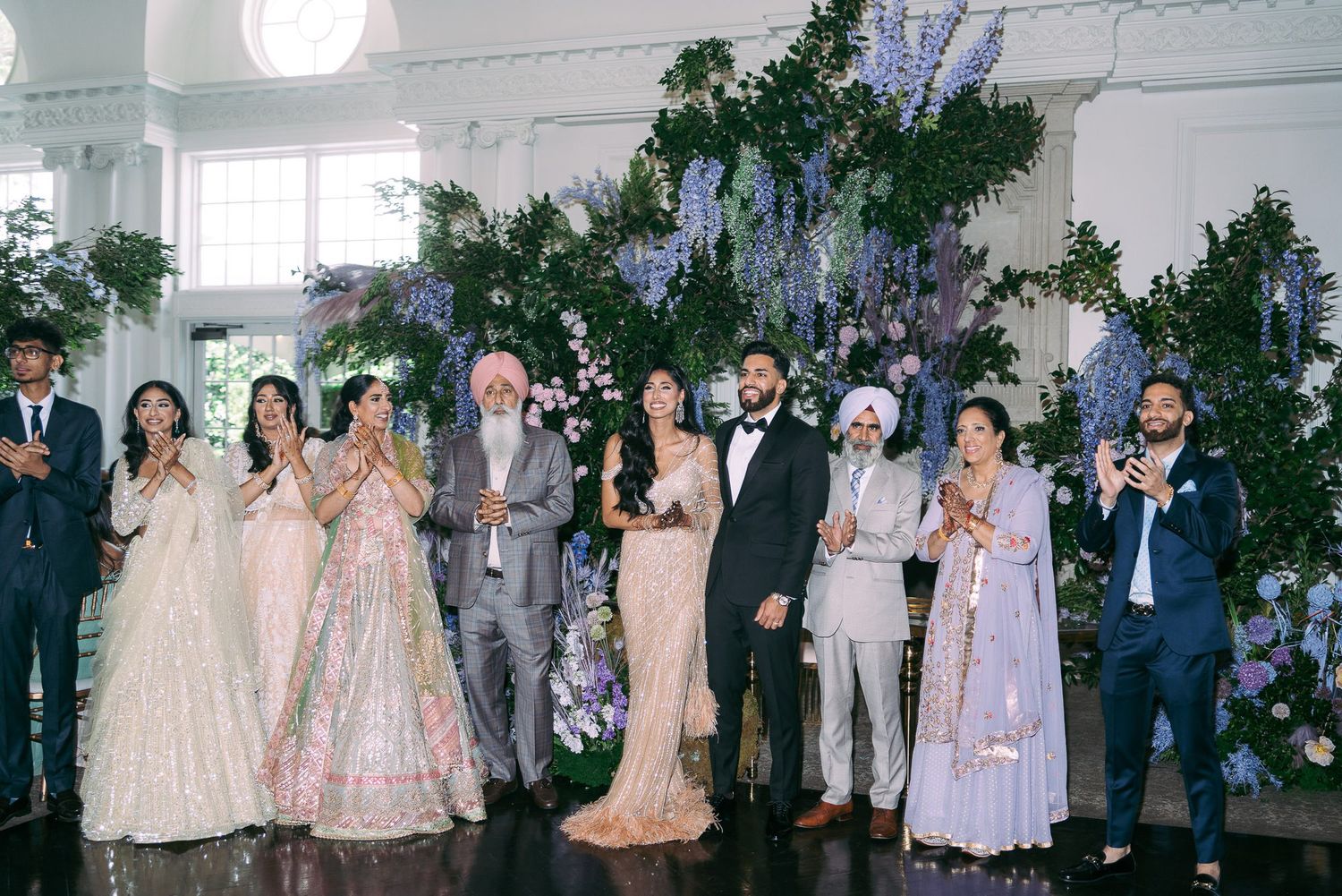 Wedding party in formal attire poses for group photos at an elegant outdoor venue with floral decorations.