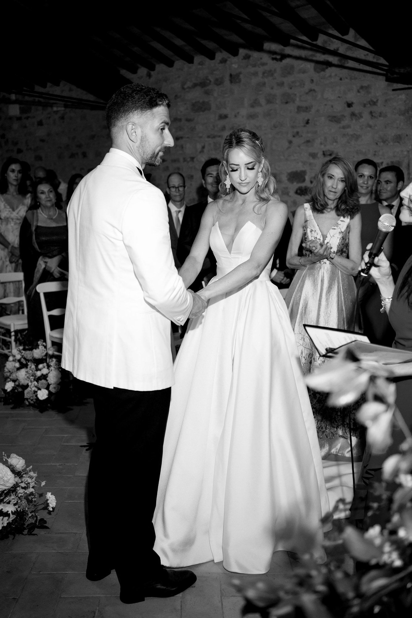 Wedding couple and guests dancing together at an elegant stone venue in black and white photography.