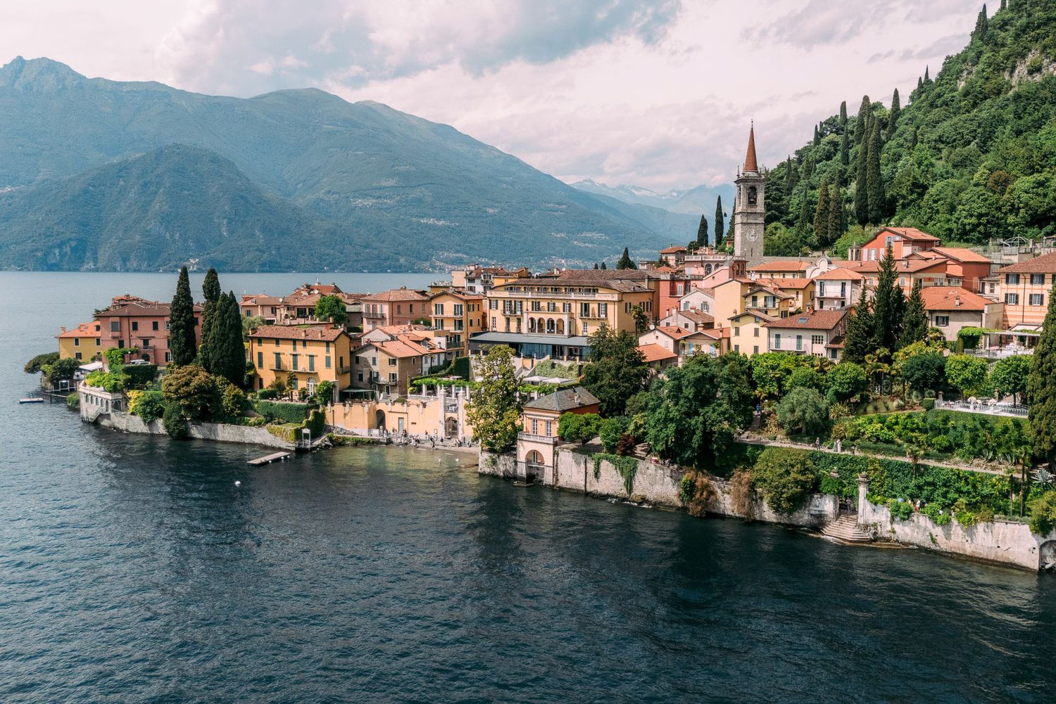 Panoramic view of Varenna village along Lake Como in Italy with historic buildings and mountains in the background.