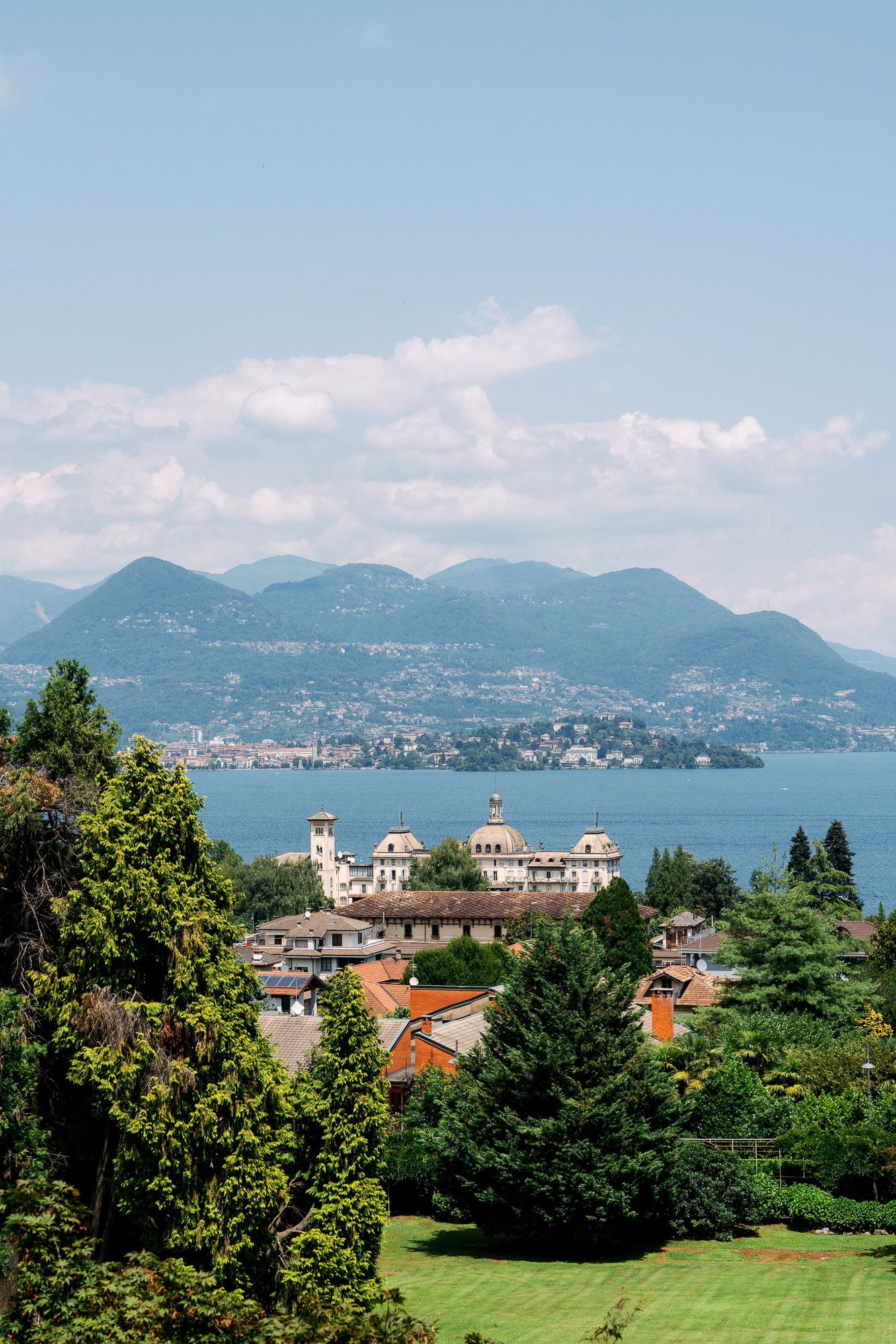 Panoramic view of Lake Maggiore with mountains, buildings, and lush greenery in Stresa, Italy.