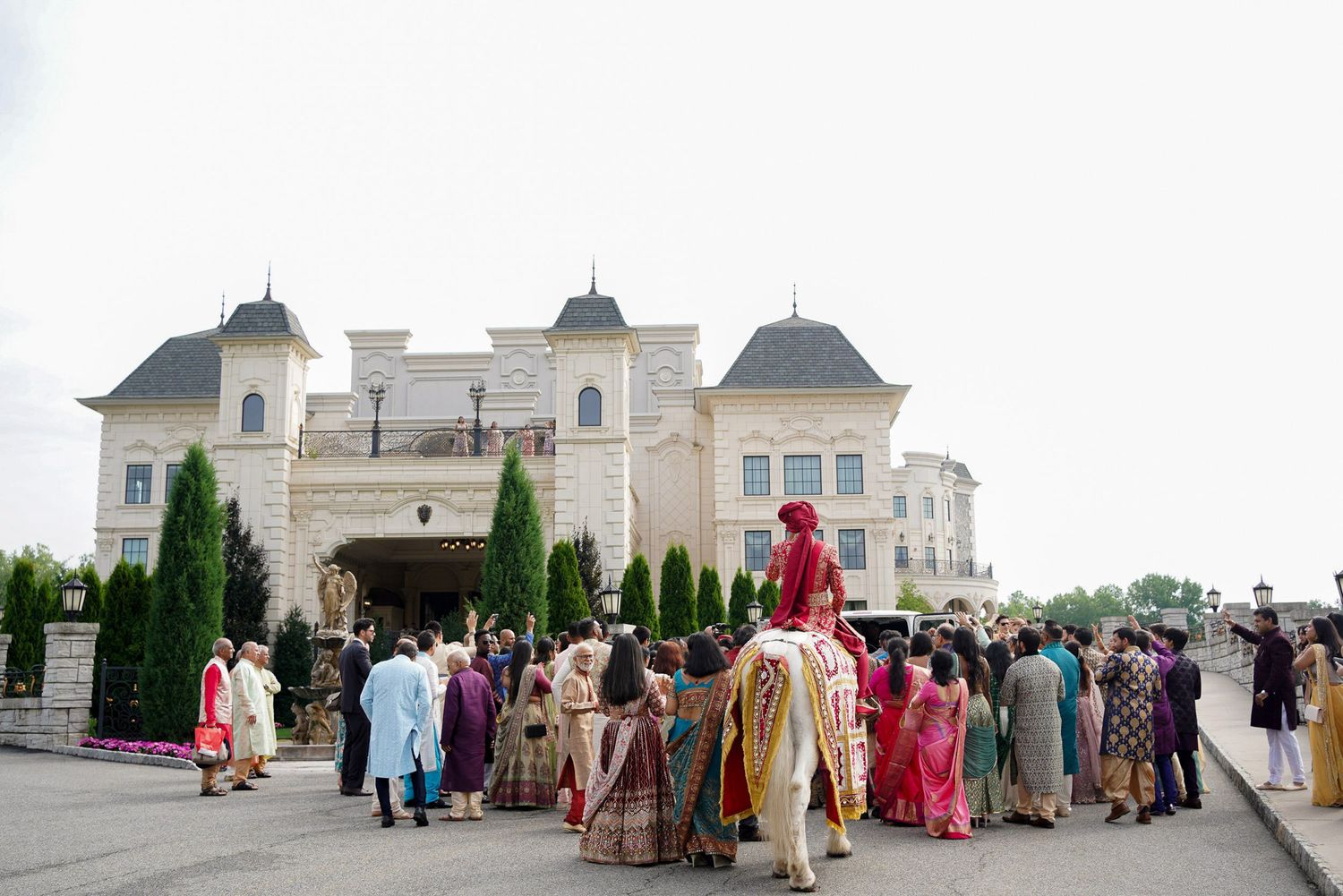A panoramic view of people gathering outside a grand white building with domed architecture.