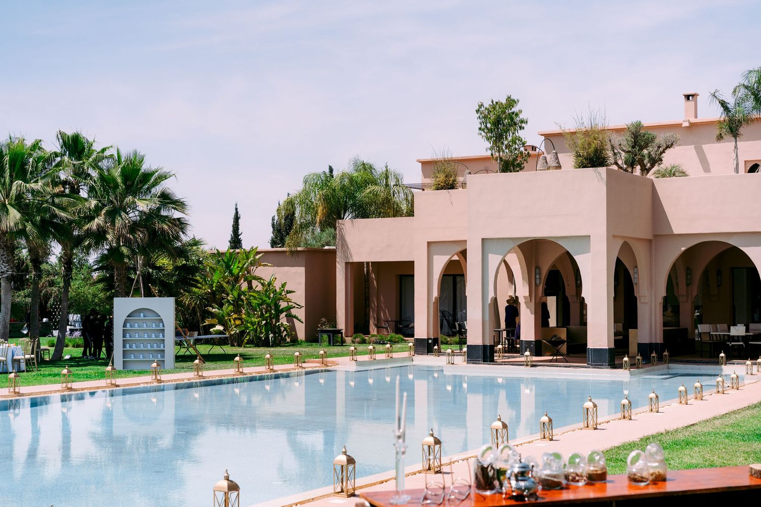 A luxurious swimming pool at a resort surrounded by pink stucco buildings and tropical landscaping in the background.