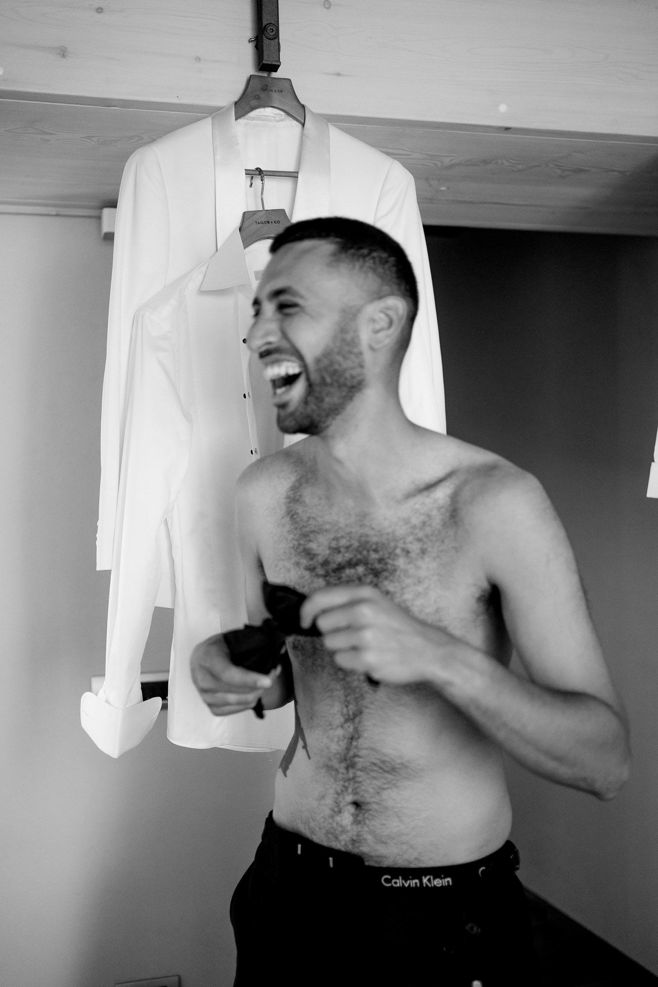 A series of black and white photos showing someone trying on different white shirts and tank tops.