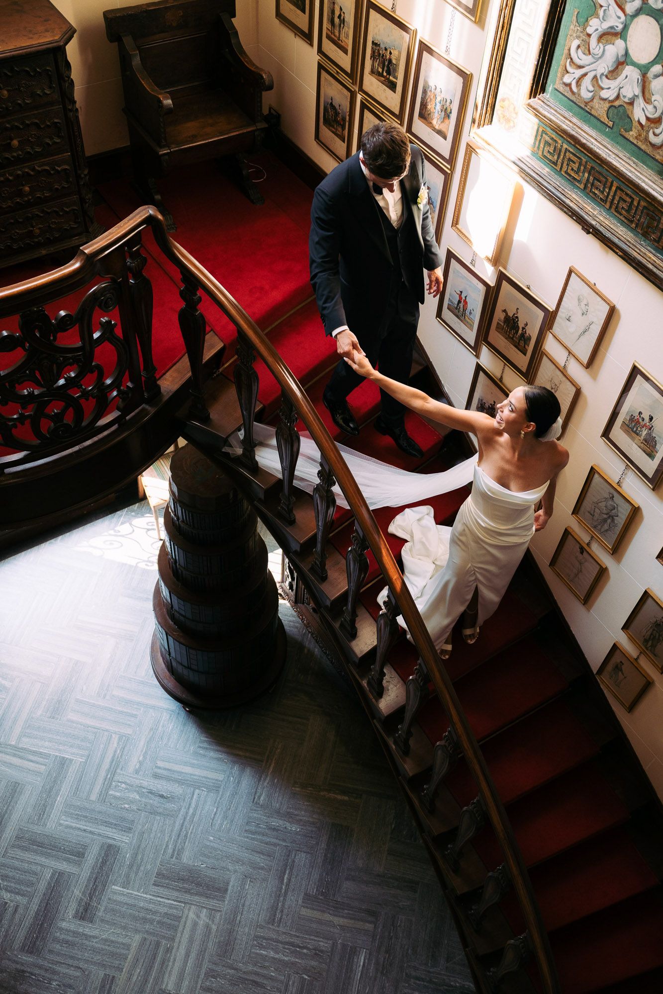 A sequence of images showing two people walking down a staircase with artwork hanging on the walls.