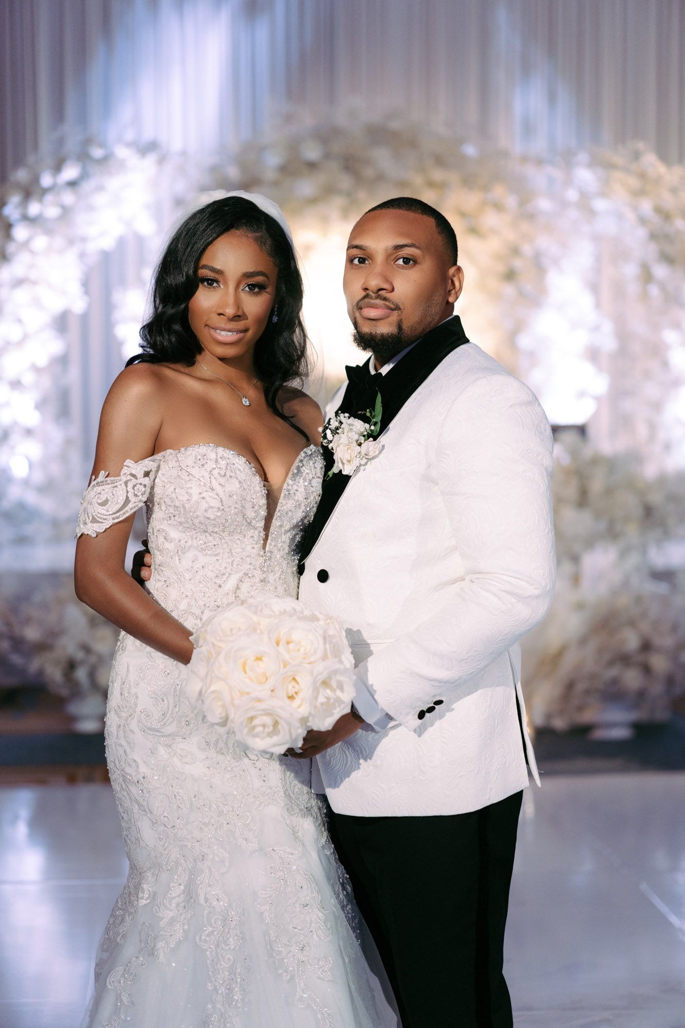 A romantic wedding photoshoot featuring a couple in elegant white attire posing together against a dreamy backdrop.