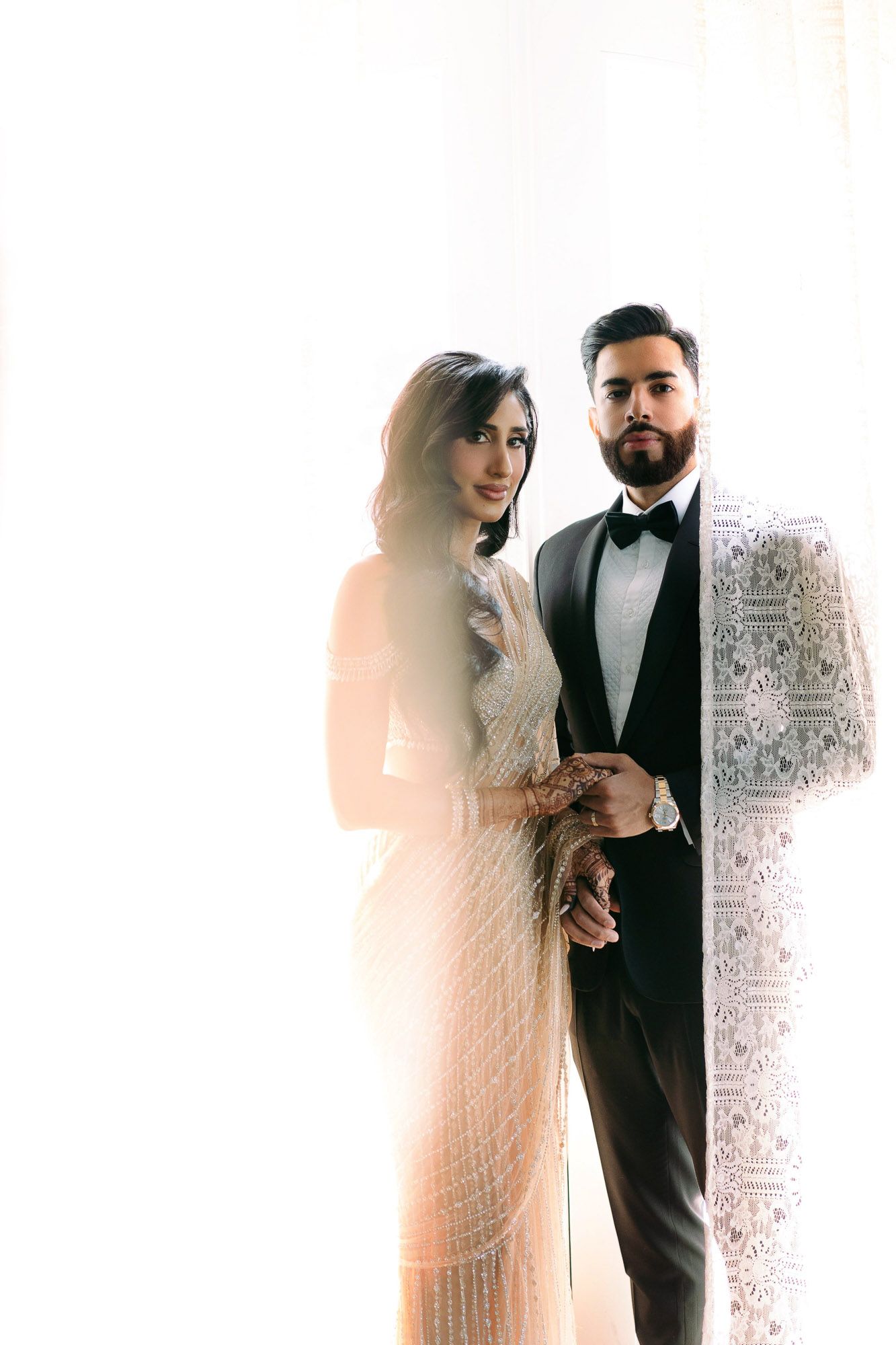 Elegant wedding couple poses in soft light with decorative wall panels creating dreamy multiple exposure effect.