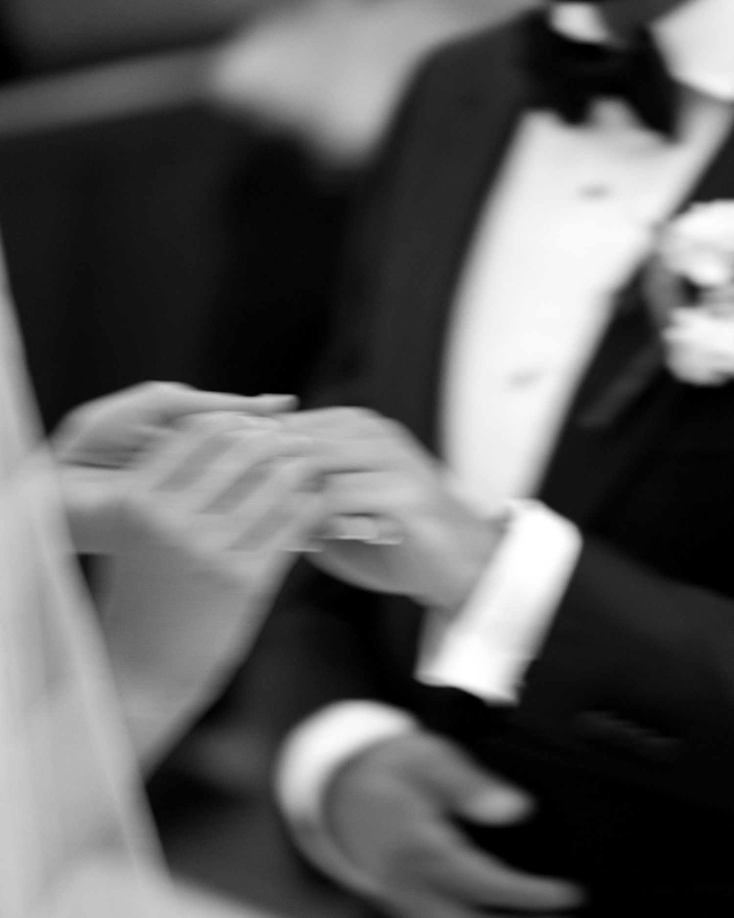 Black and white close-up photo of hands playing piano keys showing elegant finger movements.