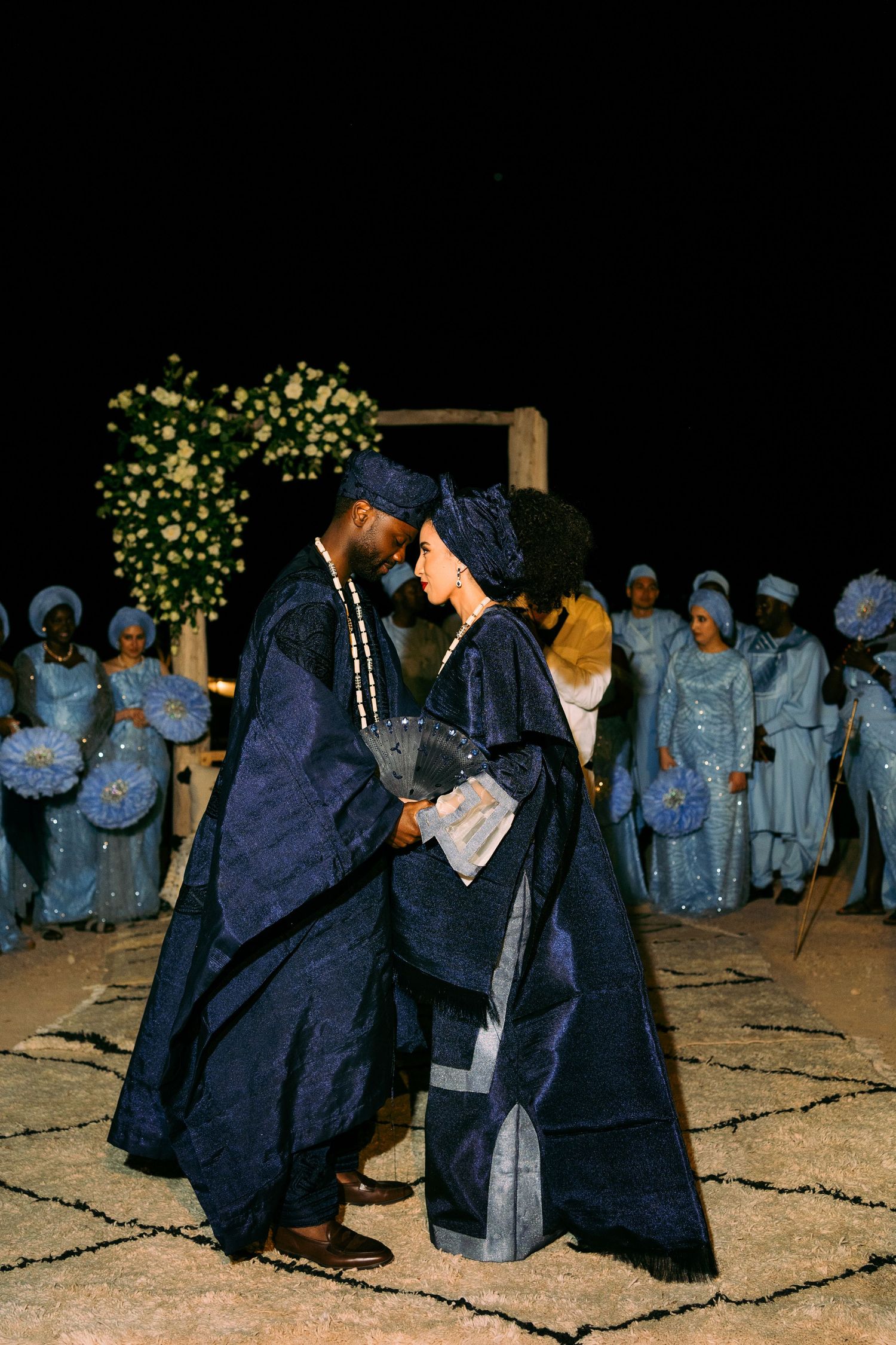 Group dressed in traditional dark robes gathering at night for a cultural celebration.