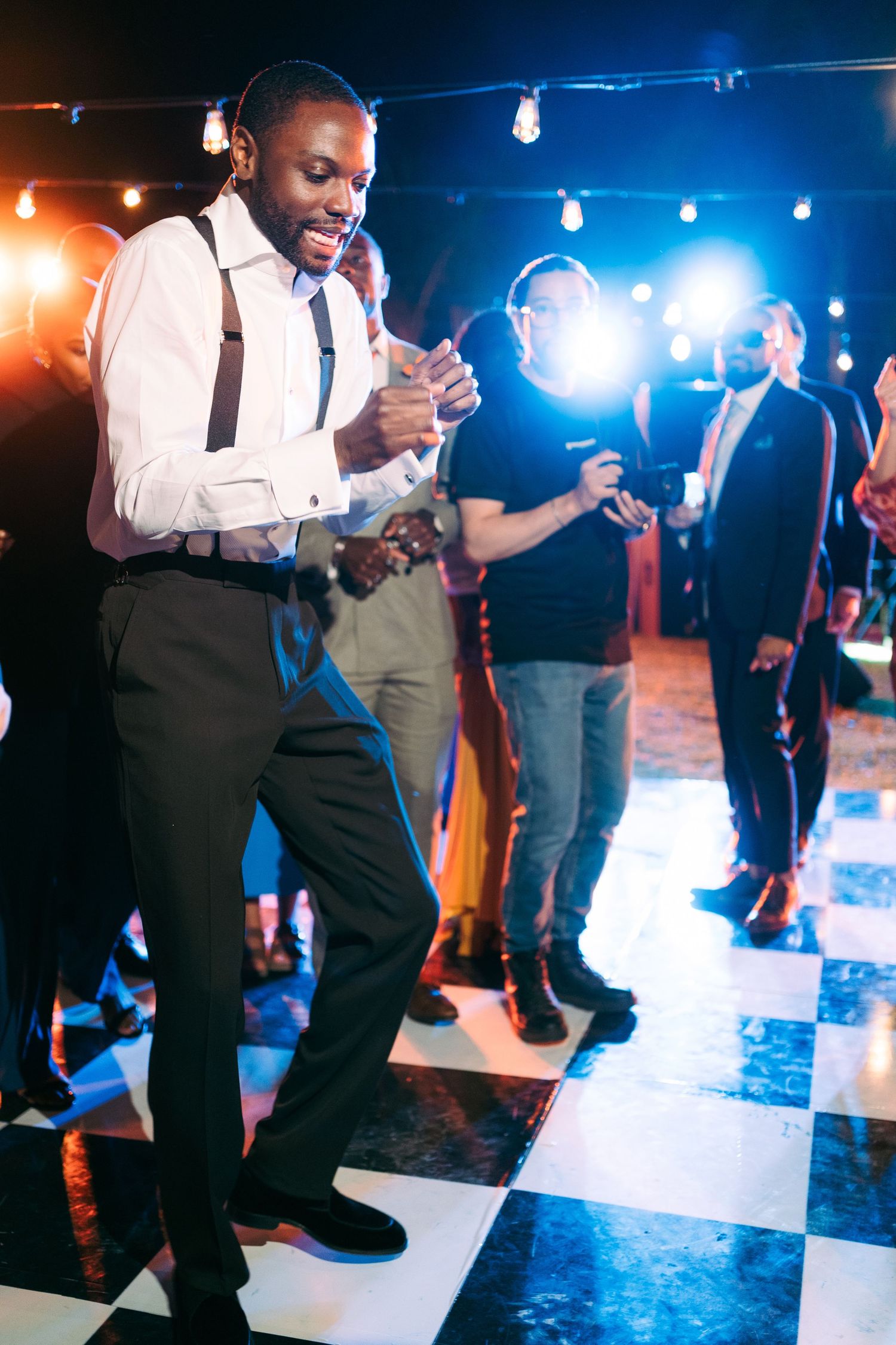 Wedding reception dance floor with blue lighting and checkered pattern showing guests dancing.