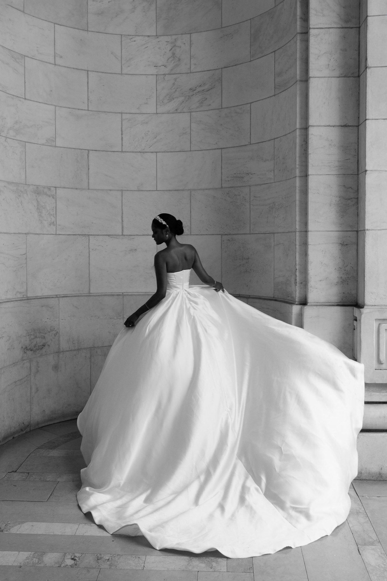 A black and white photo series showing a bride in a flowing white ball gown against marble columns and walls.