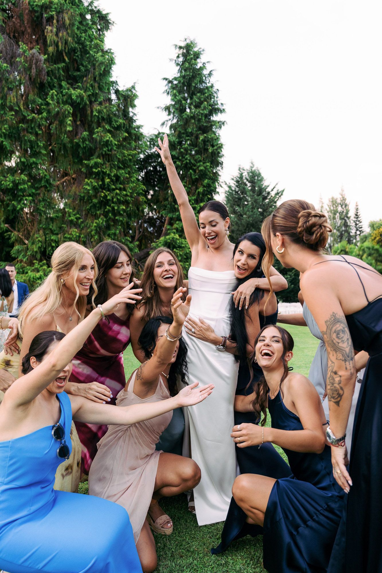 A group of friends laughing and having fun together outdoors with trees in the background.