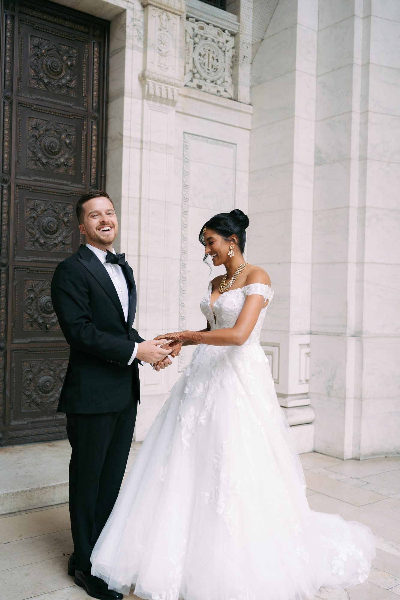 A bride and groom share a joyful moment together in a series of romantic wedding photos against ornate white columns.