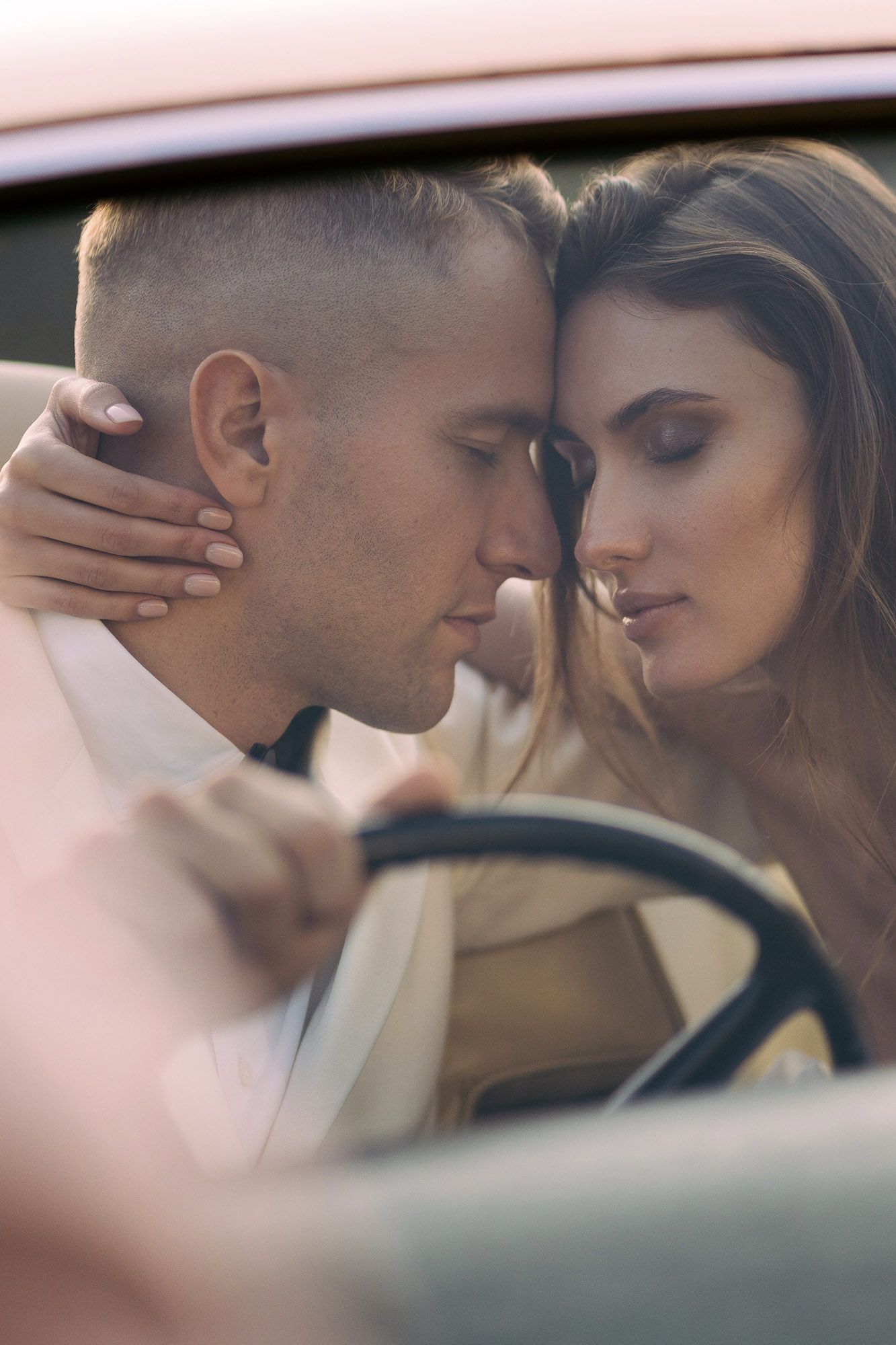 Intimate romantic moment captured between couple in car with soft lighting and dreamy atmosphere.