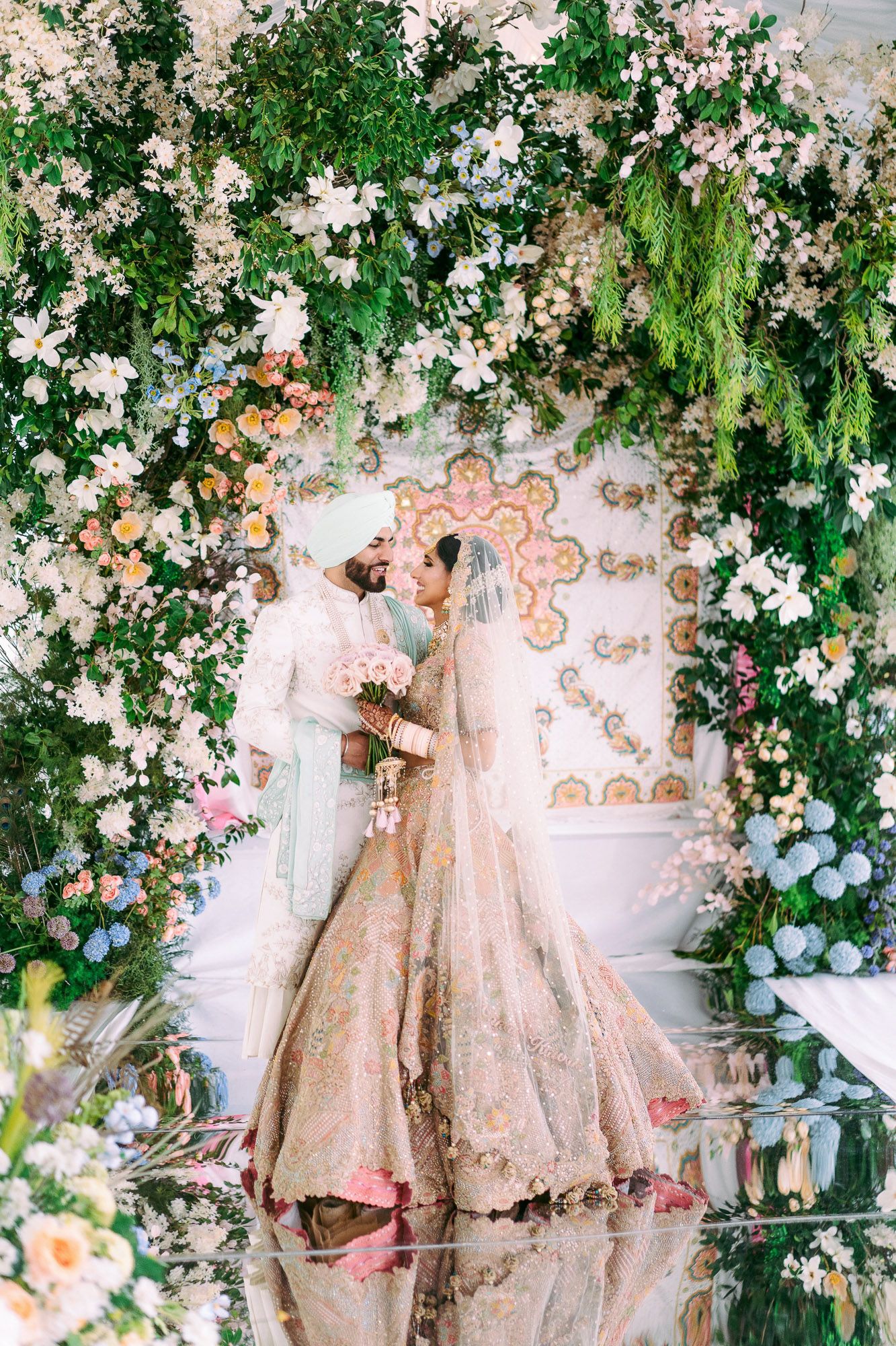 Elegant wedding dresses displayed against a romantic floral backdrop with cascading white flowers and greenery.