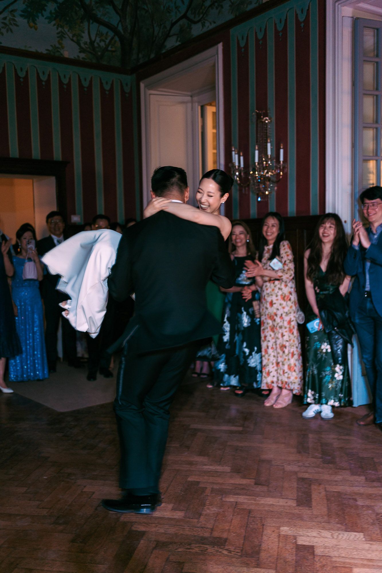 Wedding guests dance and celebrate on a wooden dance floor during a lively reception party.