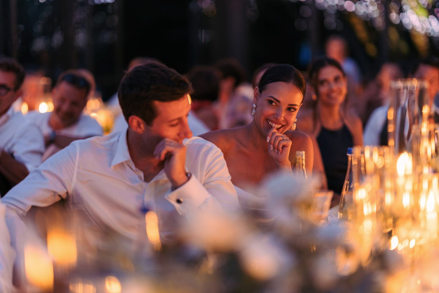 Guests enjoying an intimate candlelit dinner reception with warm ambient lighting and glowing conversations.