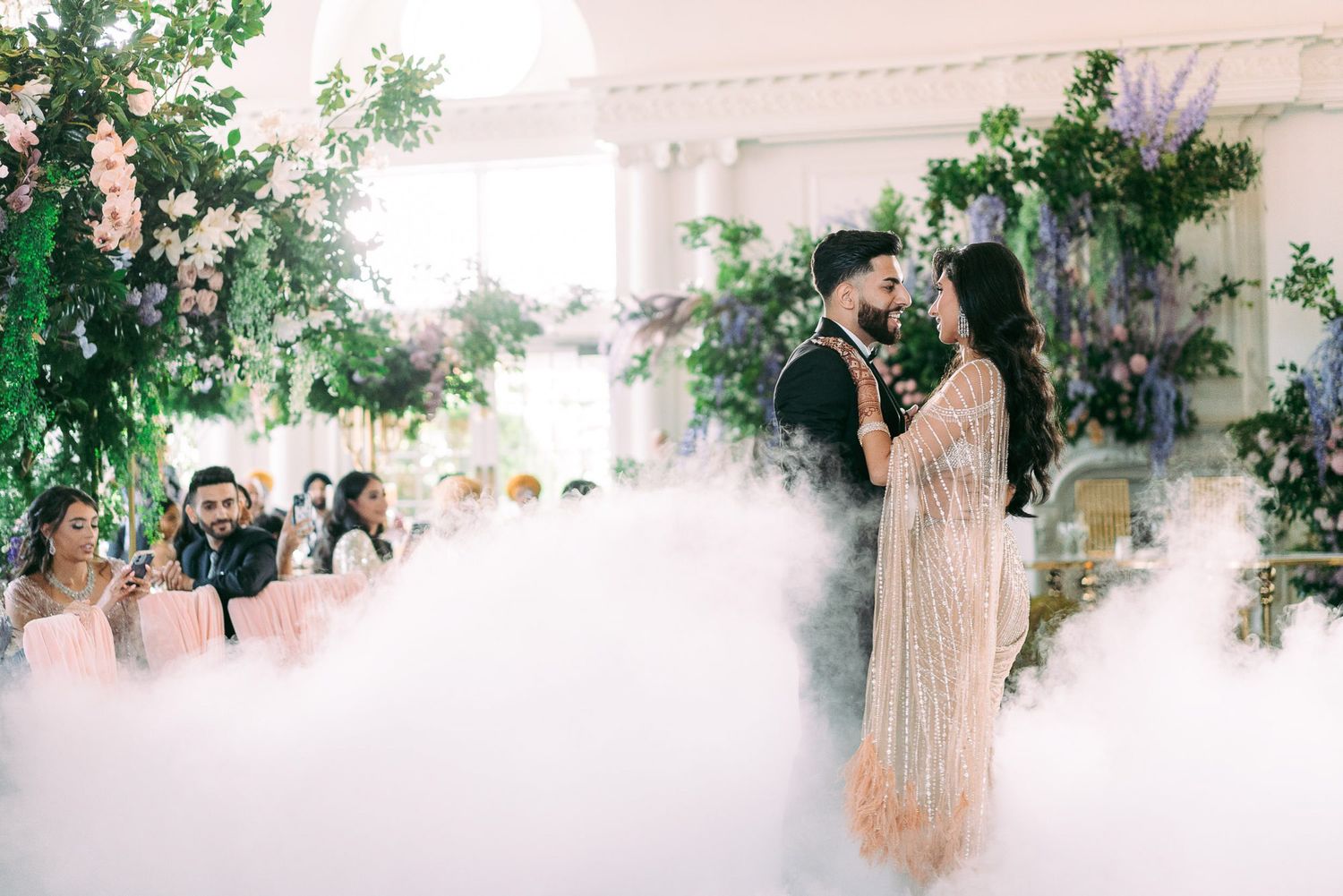 Wedding ceremony scene with smoke and greenery creating a dreamy atmosphere in an outdoor venue.
