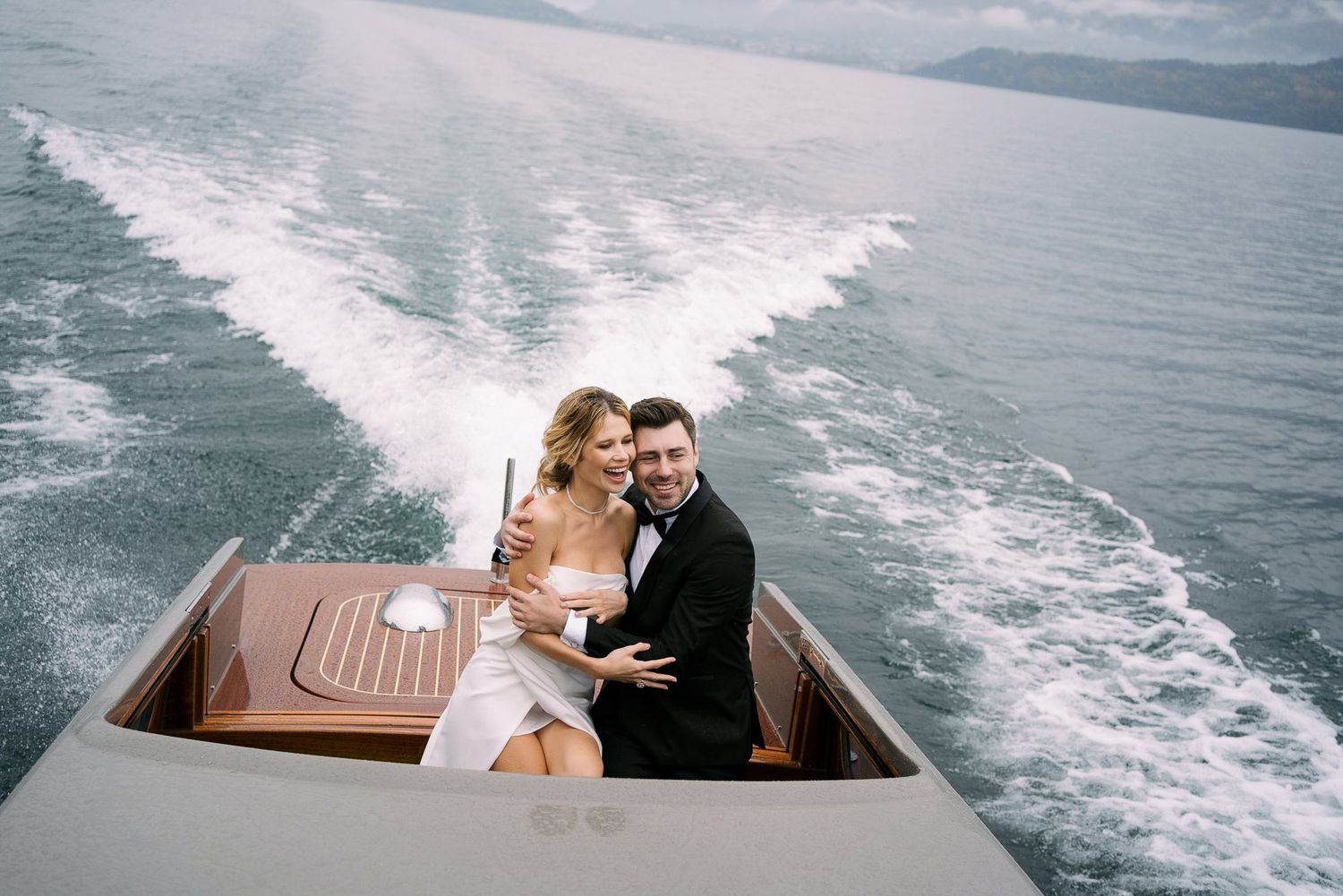 Couple enjoying a romantic boat ride across a lake leaving white wake trails in the water.