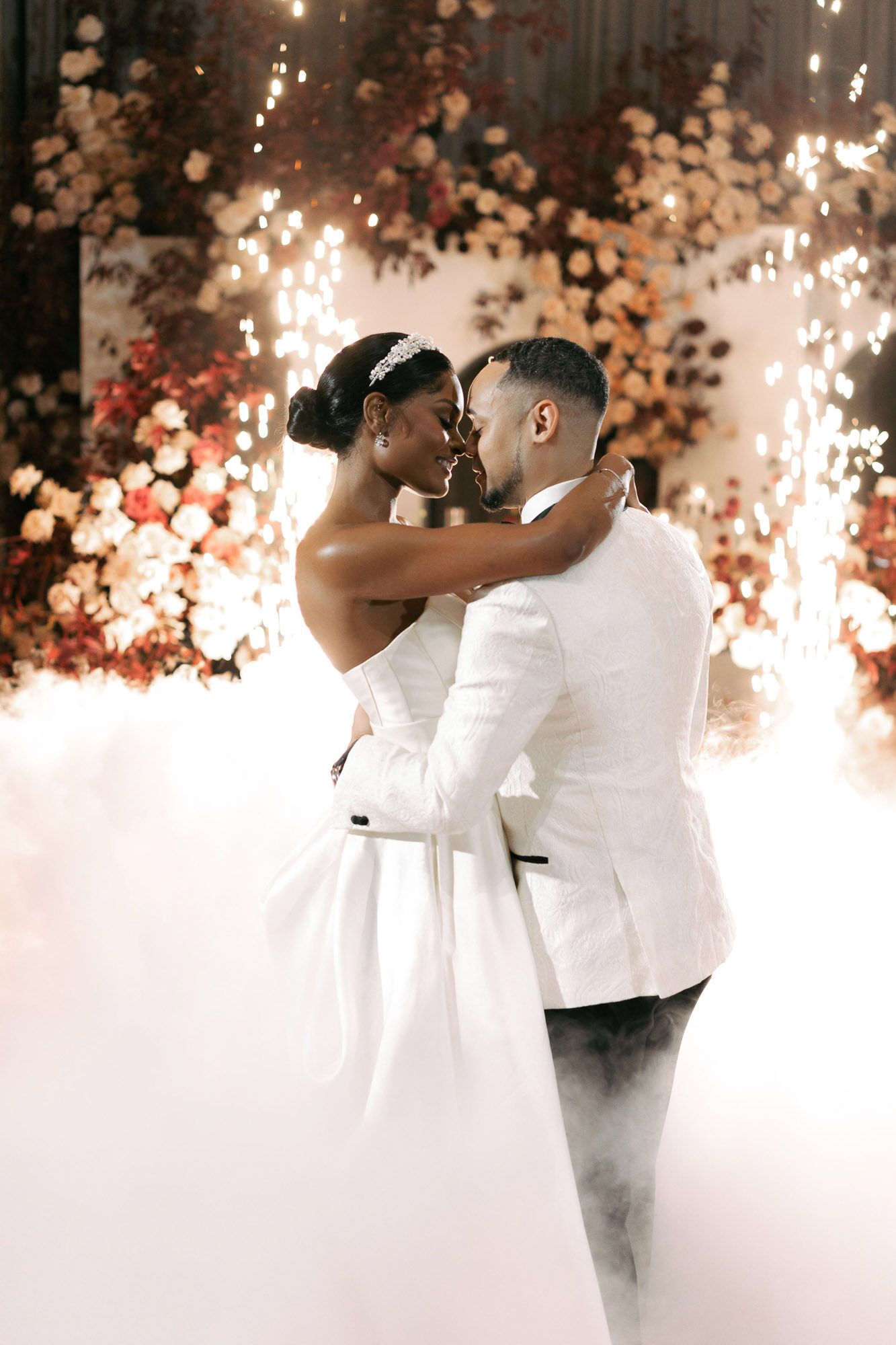 A romantic wedding couple shares their first dance surrounded by dreamy smoke effects and soft lighting.