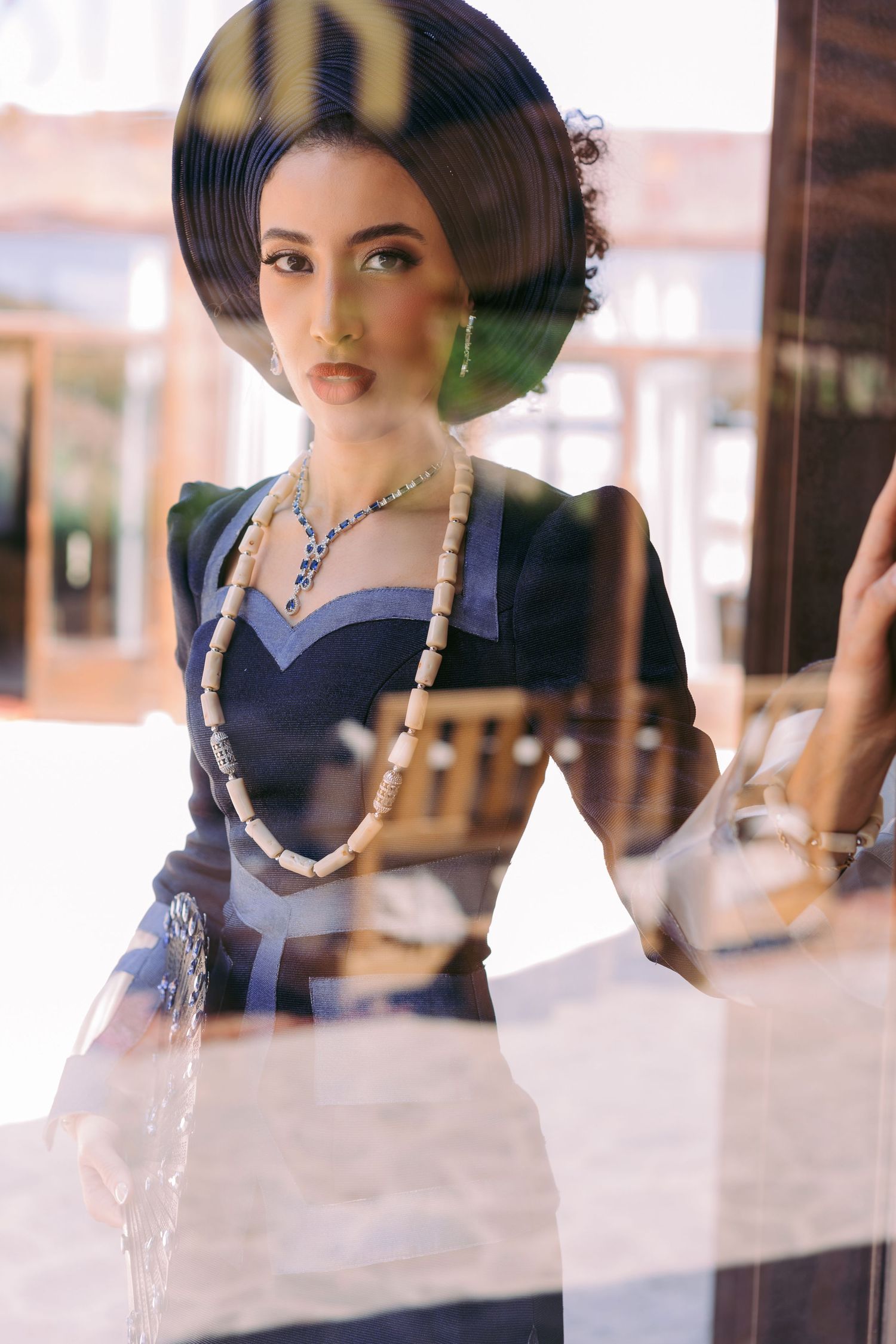 Fashion photo series of a model in traditional Asian styling wearing pearls against a blurred interior background.