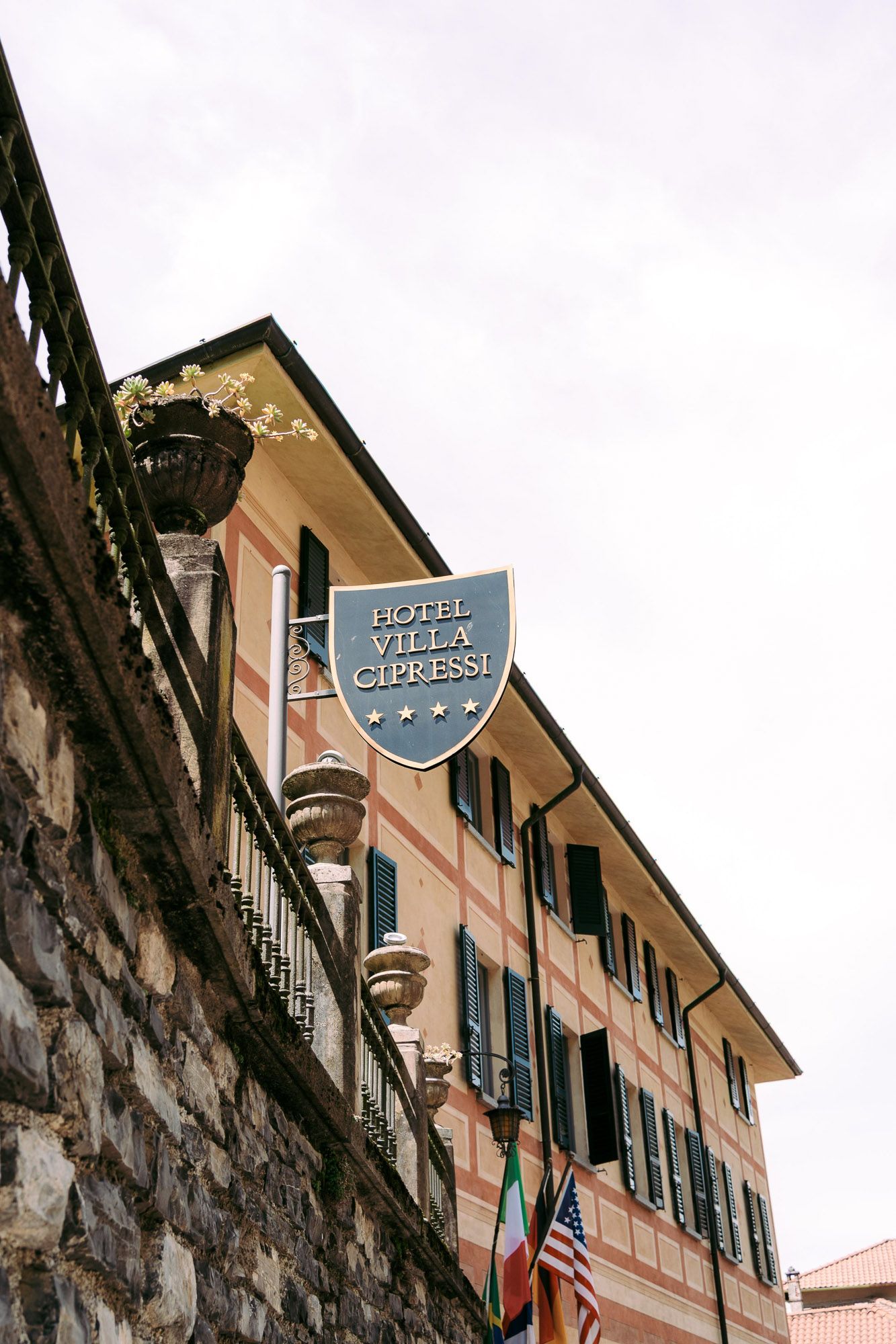 Historic Hotel Villa building with blue shutters and stone walls along a narrow street in Italy.