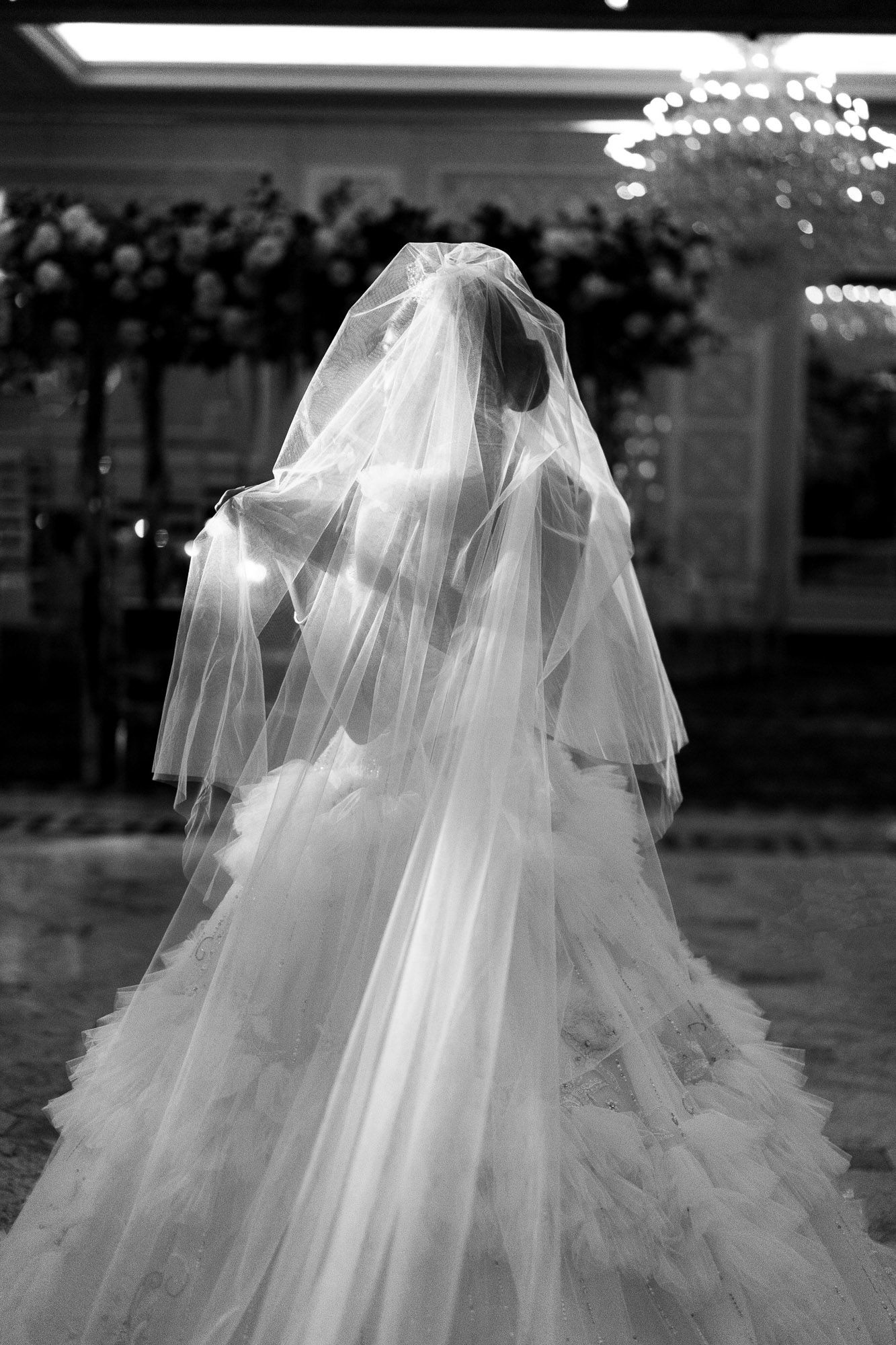 A dreamy black and white wedding dress with flowing tulle veil captured in a romantic outdoor setting.