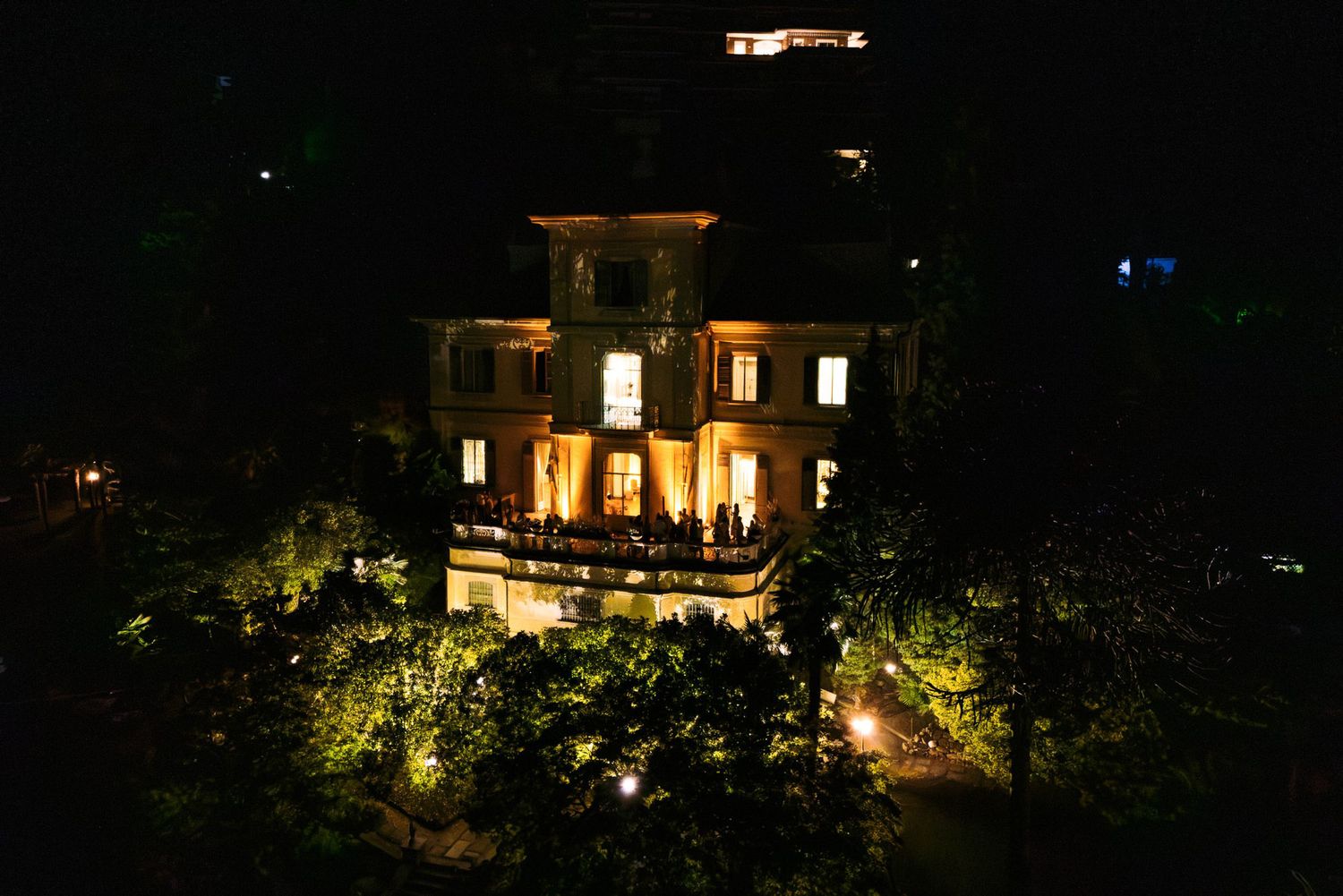 A series of illuminated houses nestled in a dark hillside create a peaceful nighttime scene.