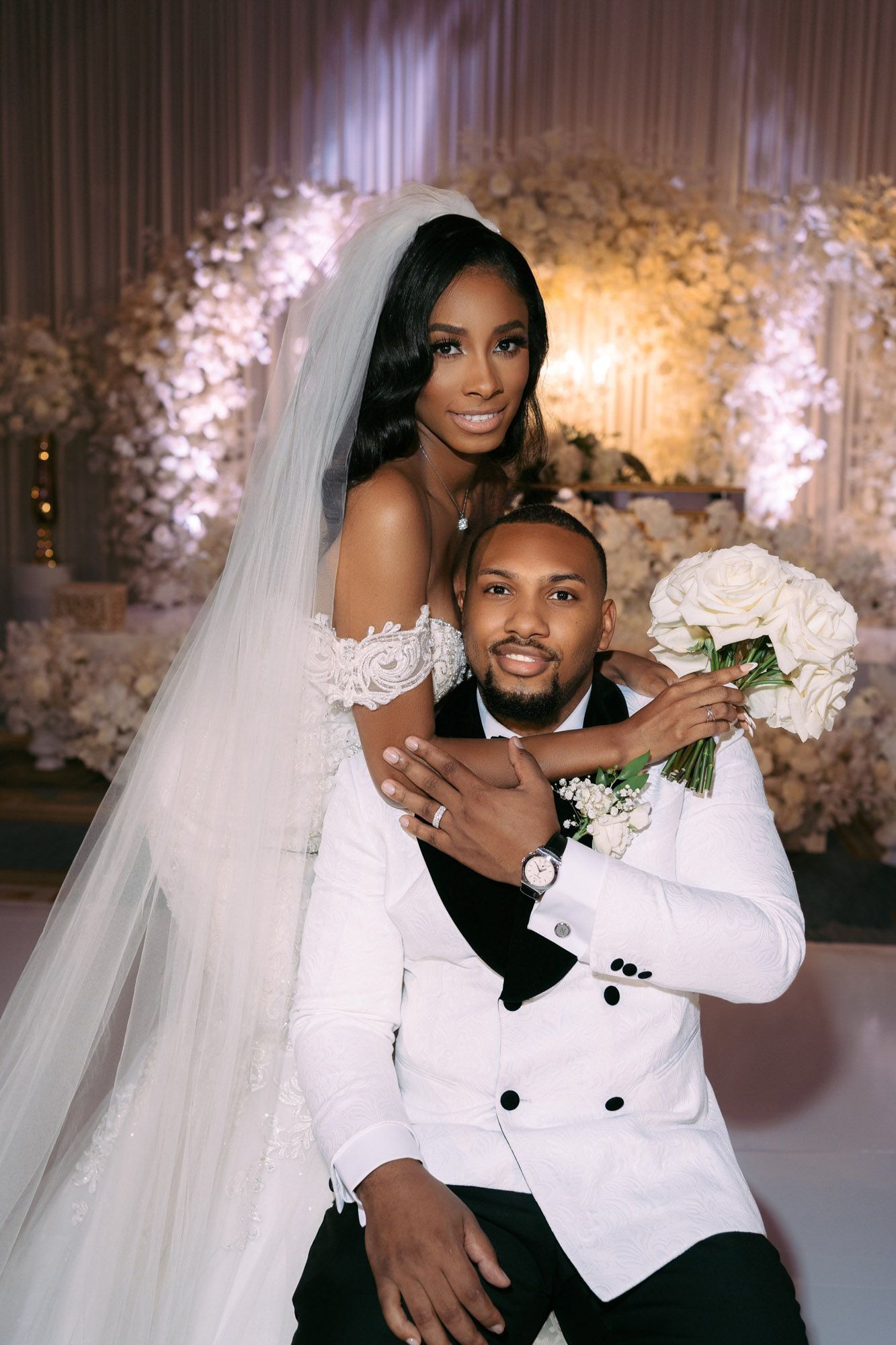 A romantic wedding photoshoot series showing a couple in traditional white wedding attire posing together in front of floral decor.
