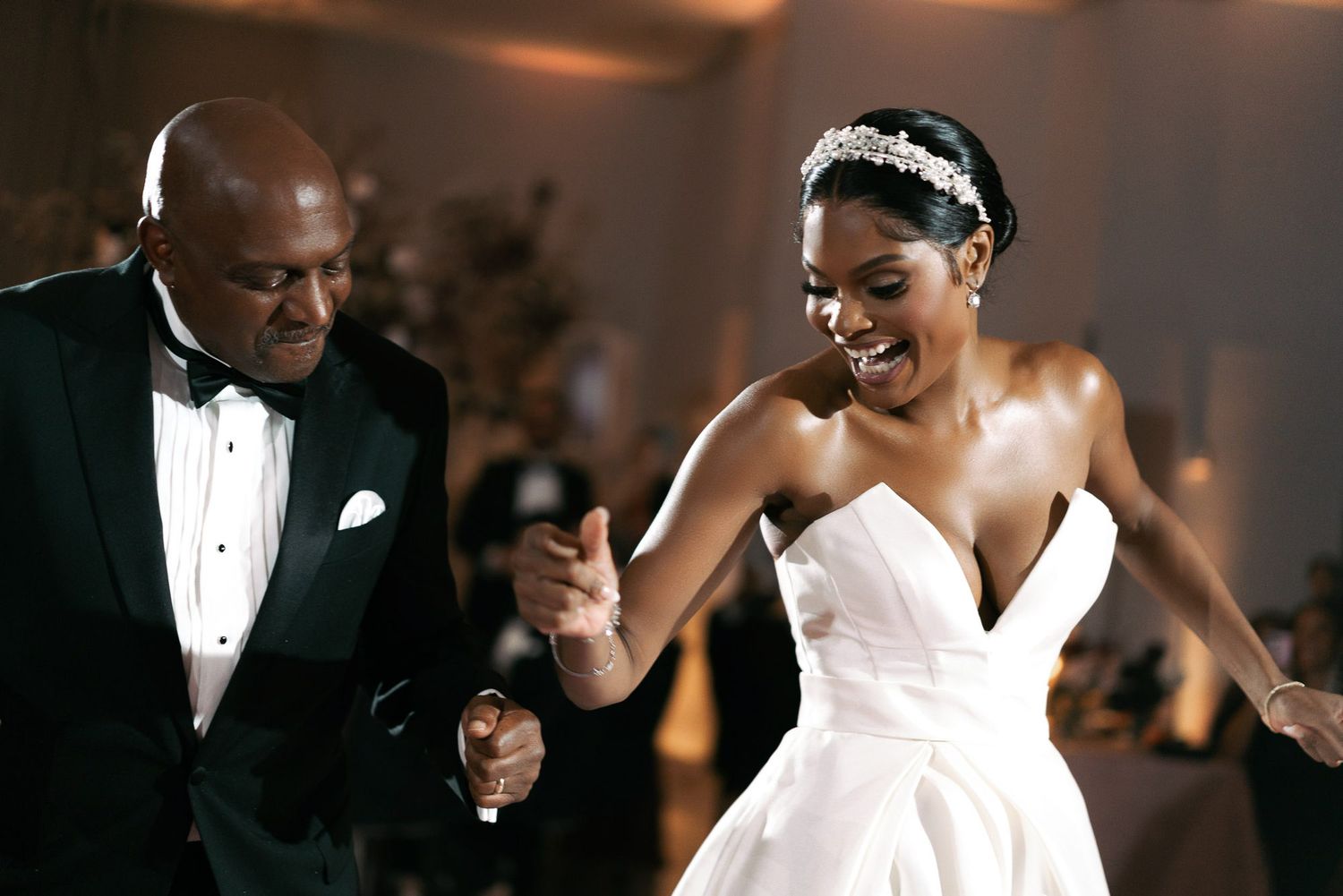 A wedding couple dances together at their elegant reception while guests look on with joy.