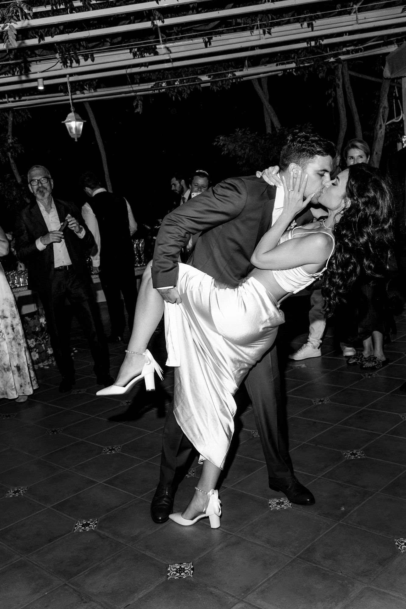 Dancers perform a dramatic dip move during a swing dance performance in black and white photography.