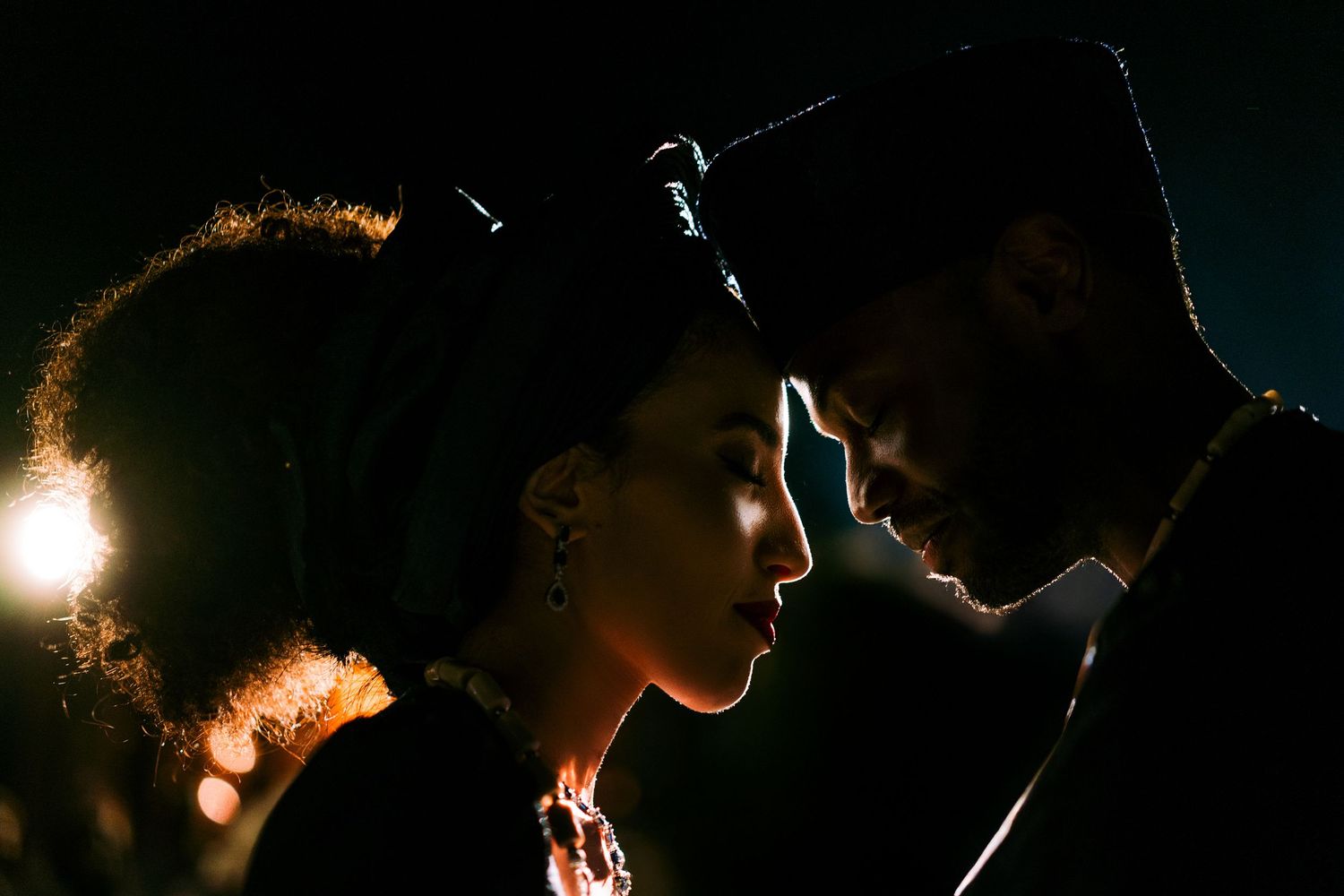 Romantic silhouettes of a couple in intimate poses against dark background.