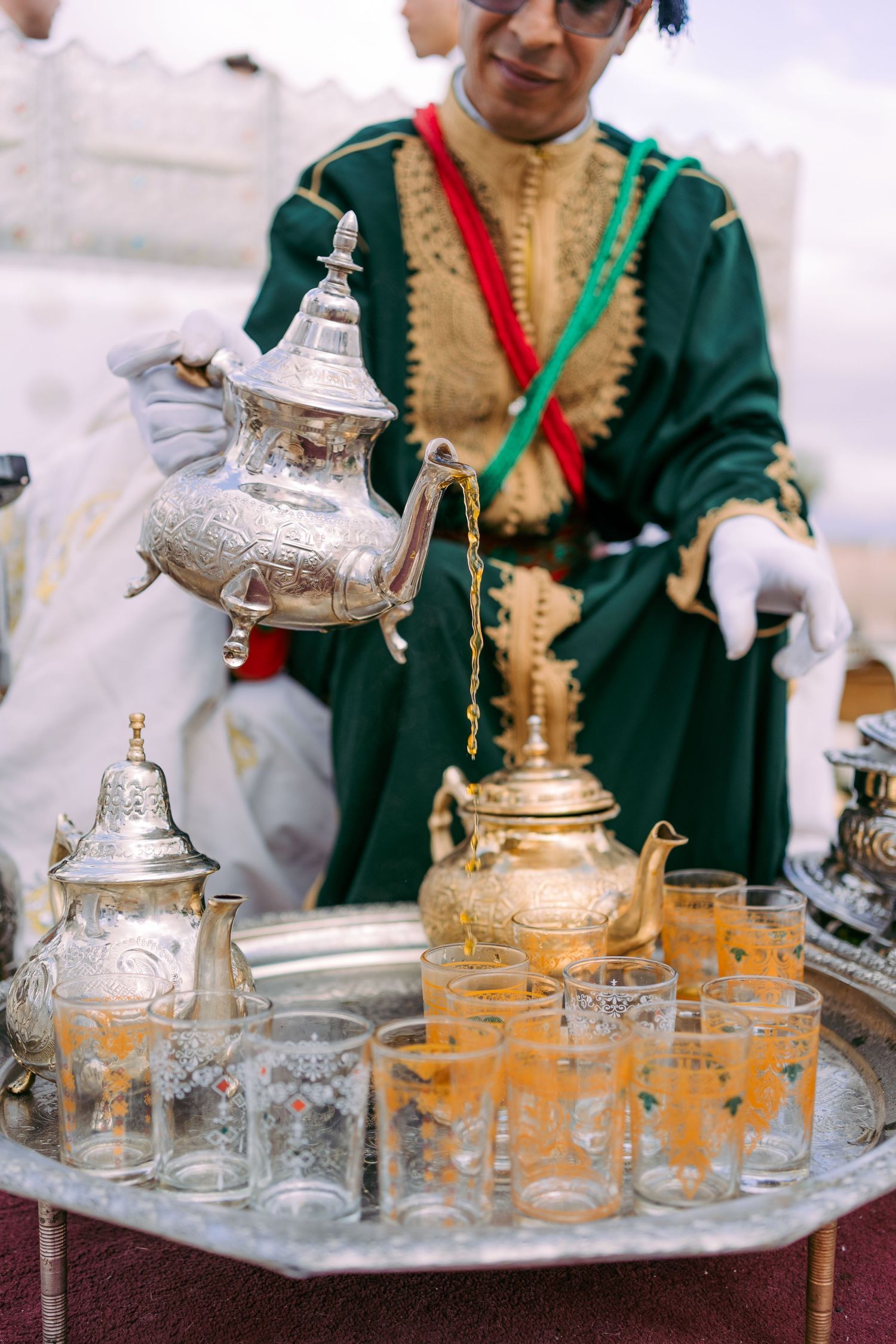 Ornate silver teapots and traditional tea glasses arranged on decorative serving trays.